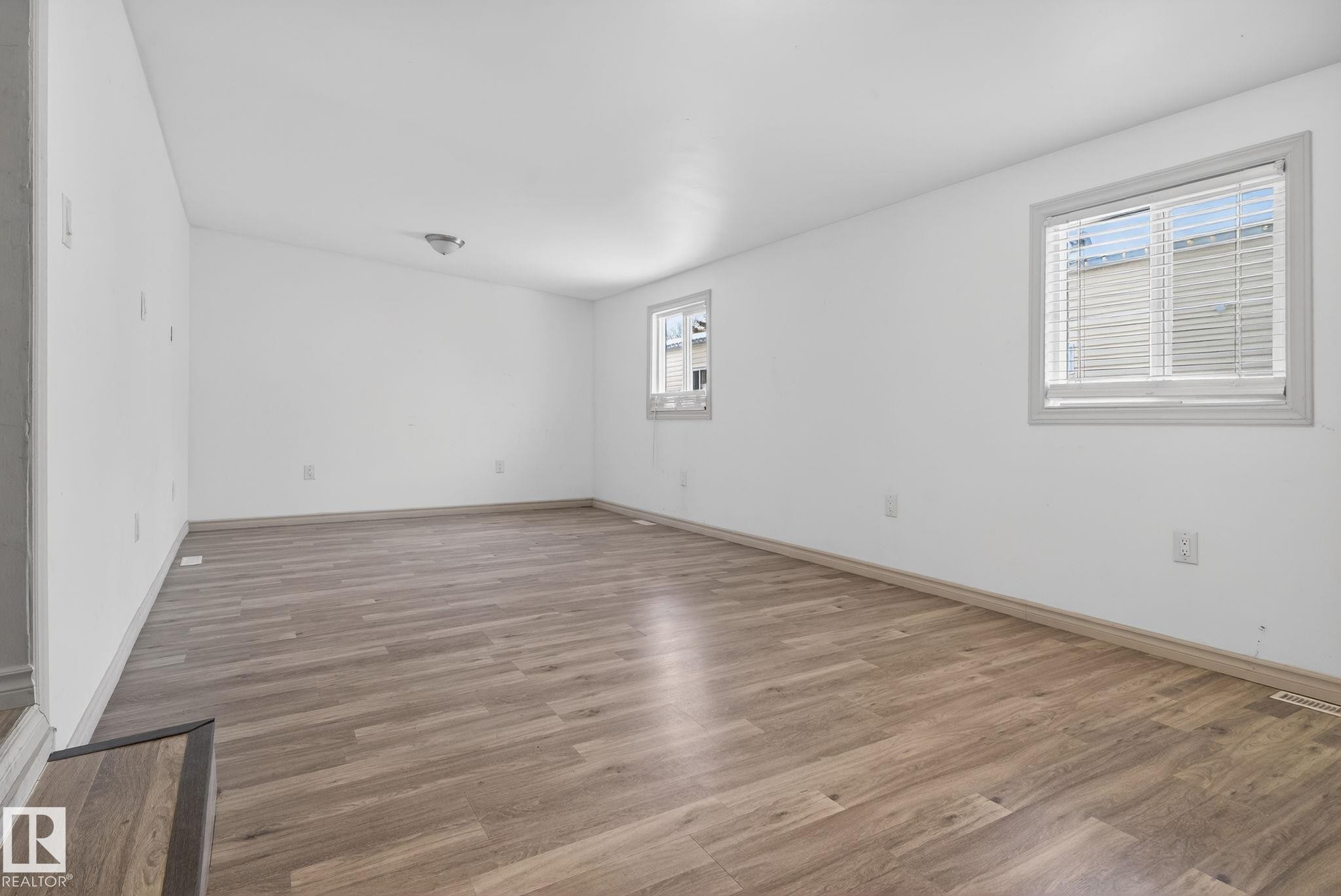 Spacious room featuring wood-finish flooring, white walls, and two windows with blinds - 543 Evergreen Park Northwest, Edmonton, AB - Indoor Photo Showing Other Room