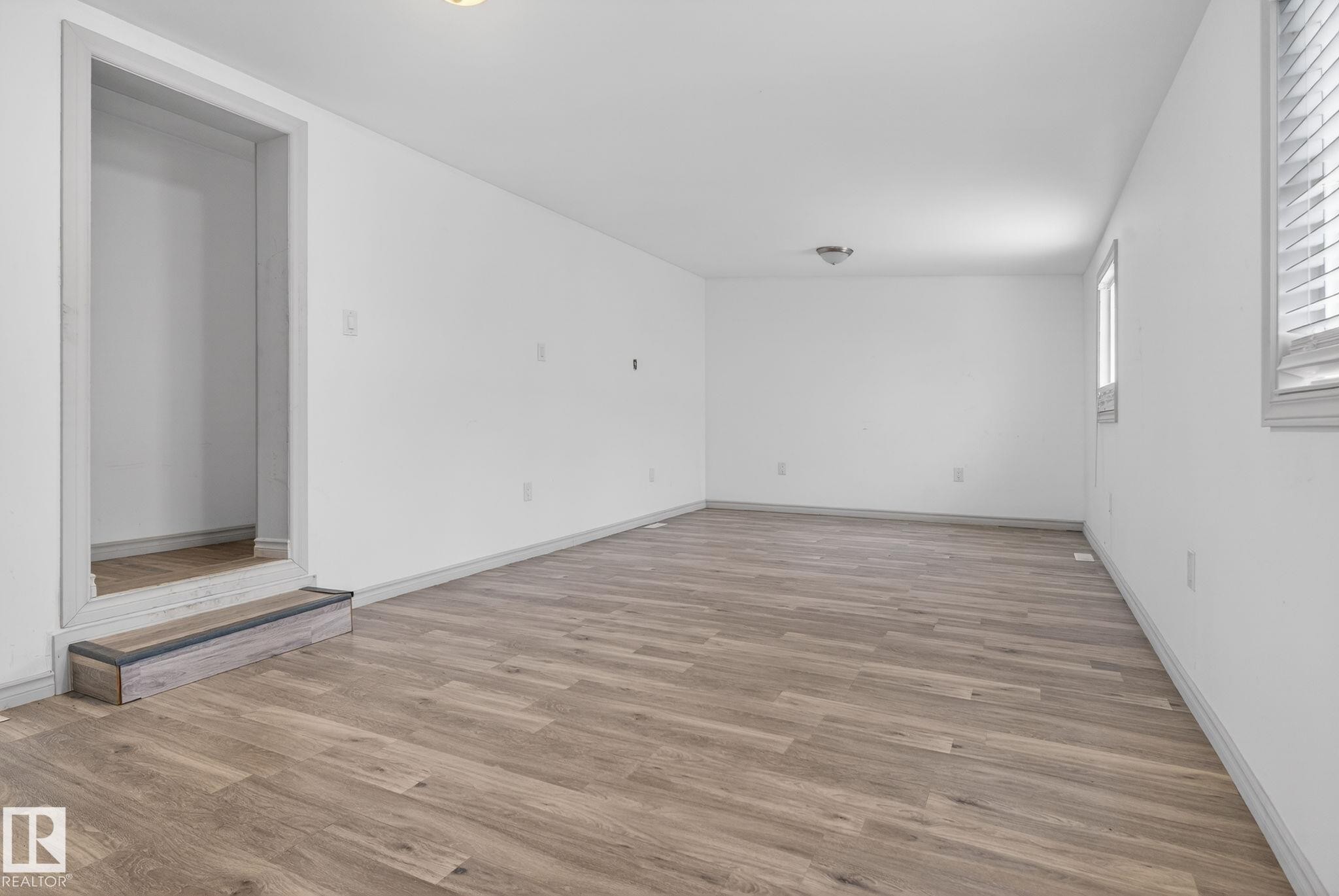 Spacious room featuring wood-finish flooring, crisp white walls, and multiple windows with blinds for natural light - 543 Evergreen Park Northwest, Edmonton, AB - Indoor Photo Showing Other Room