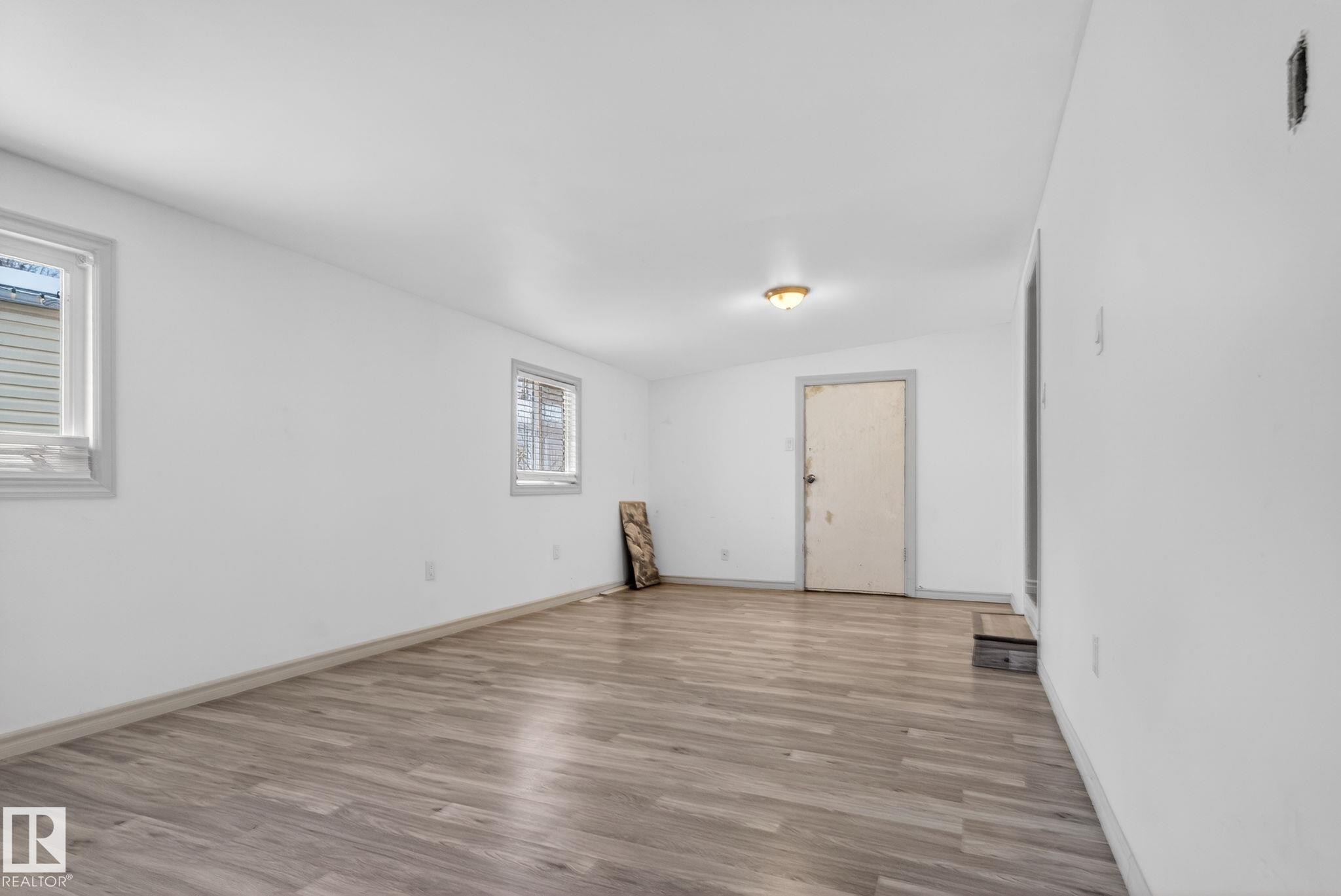 Spacious room featuring wood-finish flooring, white walls, and two windows - 543 Evergreen Park Northwest, Edmonton, AB - Indoor Photo Showing Other Room