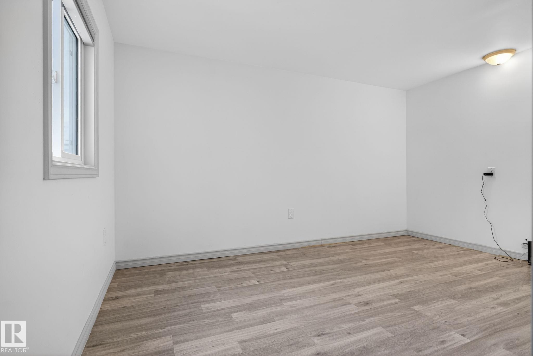 Spacious room featuring wood-finish flooring, white walls, and a single pane window - 543 Evergreen Park Northwest, Edmonton, AB - Indoor Photo Showing Other Room