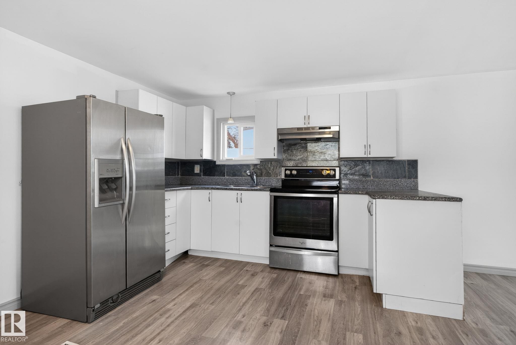 Kitchen featuring wood-finish flooring, white cabinetry, granite-look countertops, and a stone-tile backsplash - 543 Evergreen Park Northwest, Edmonton, AB - Indoor Photo Showing Kitchen