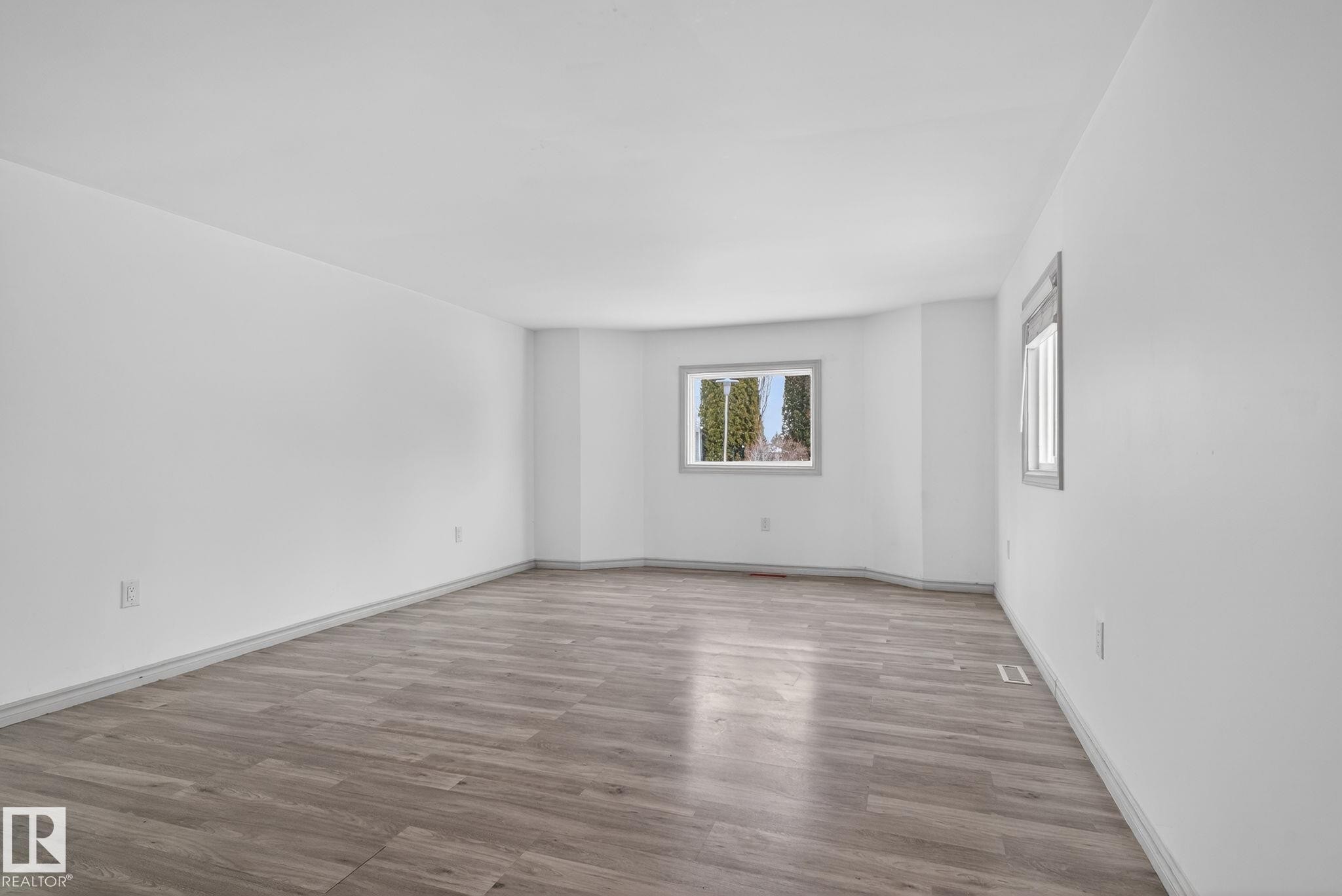 Spacious room featuring wood-finish flooring, white walls, and two windows with grey trim - 543 Evergreen Park Northwest, Edmonton, AB - Indoor Photo Showing Other Room