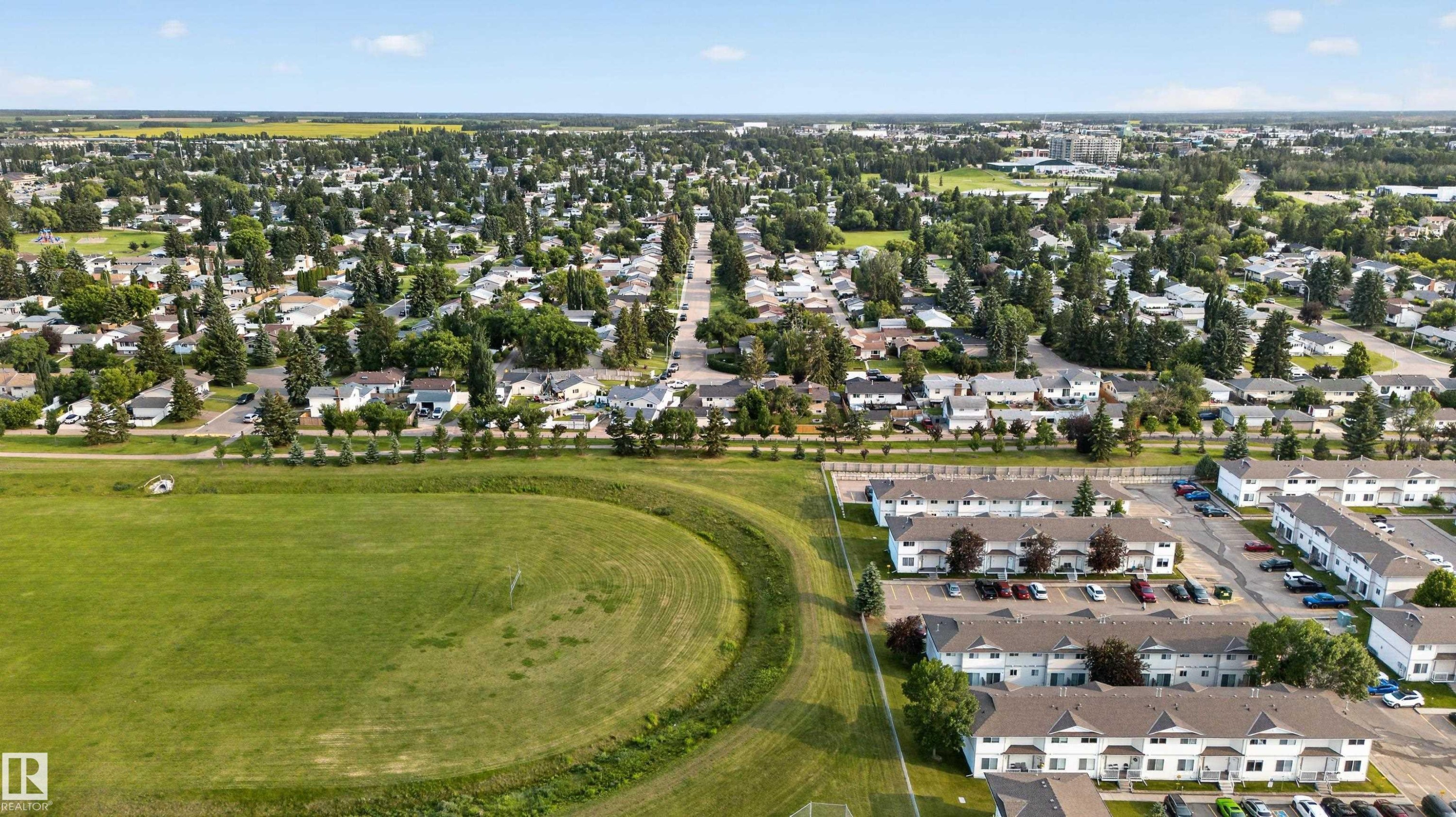 Expansive aerial perspective showcasing a residential area with a mix of single-family homes and multi-family townhomes - 33 Brookside Avenue, Spruce Grove, AB