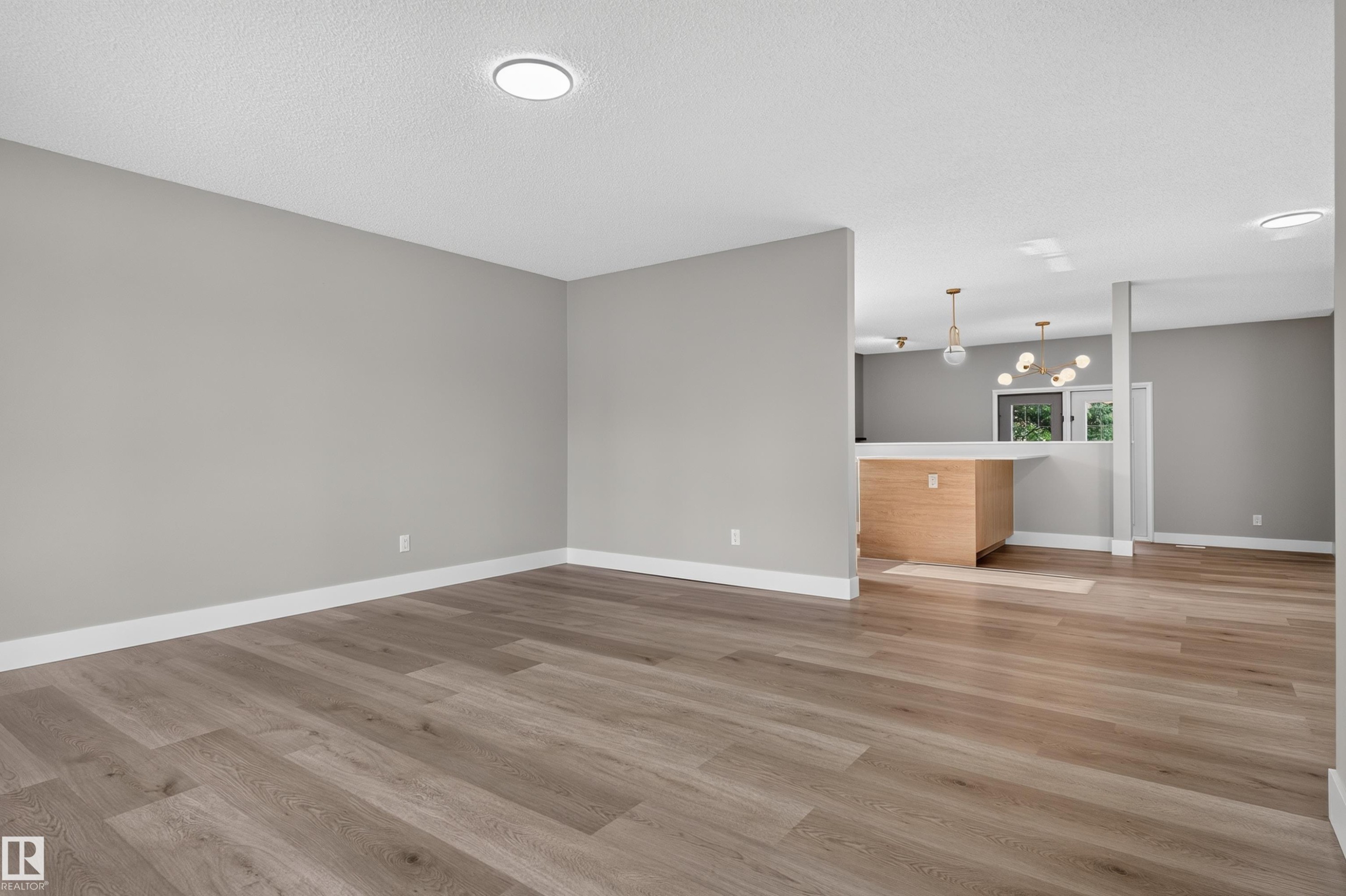 Spacious room featuring wood-finish flooring, recessed ceiling lighting, and light gray wall paint - 33 Brookside Avenue, Spruce Grove, AB