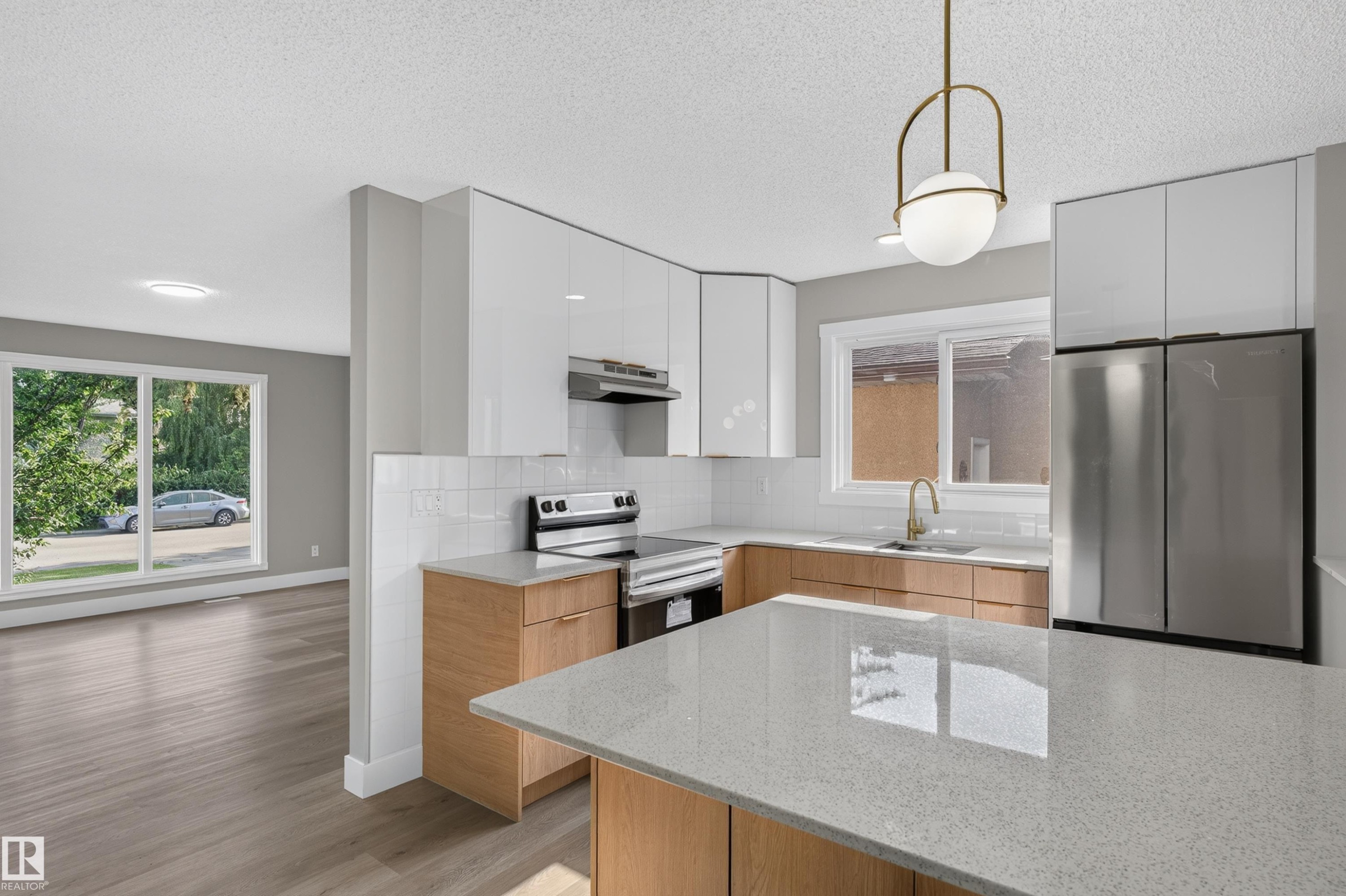 Modern kitchen featuring white upper cabinetry, wood-finish lower cabinetry, and stainless steel appliances - 33 Brookside Avenue, Spruce Grove, AB