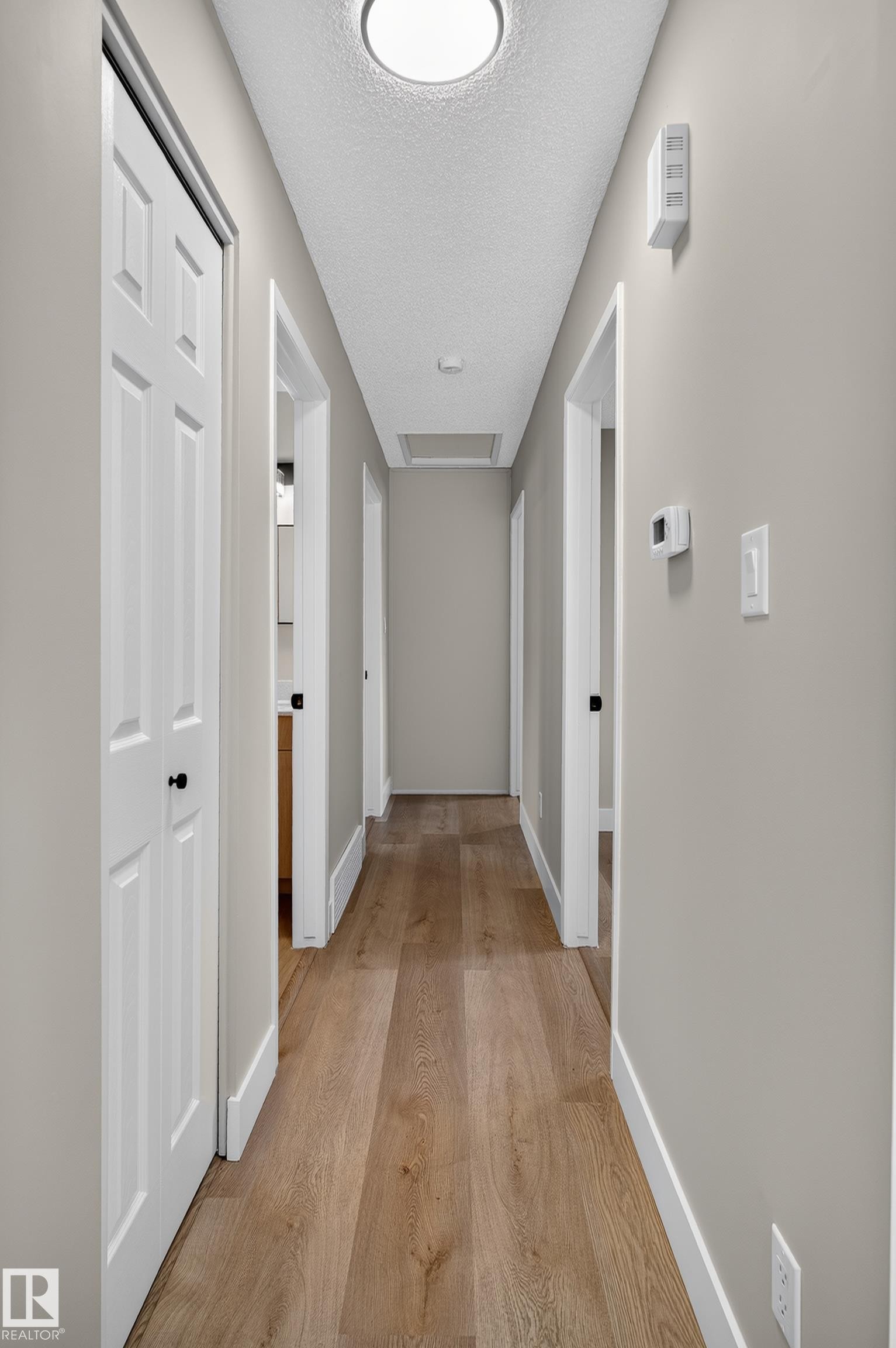 Hallway featuring wood-finish flooring, light neutral wall paint, white trim, and recessed lighting - 33 Brookside Avenue, Spruce Grove, AB