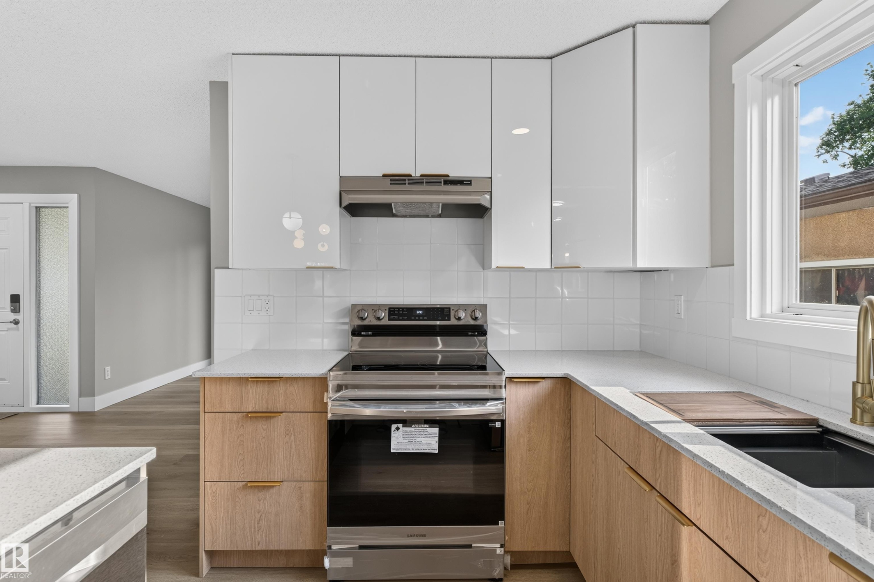 Modern kitchen featuring white upper cabinetry, wood-finish lower cabinetry, white subway tile backsplash, and light-toned countertops - 33 Brookside Avenue, Spruce Grove, AB