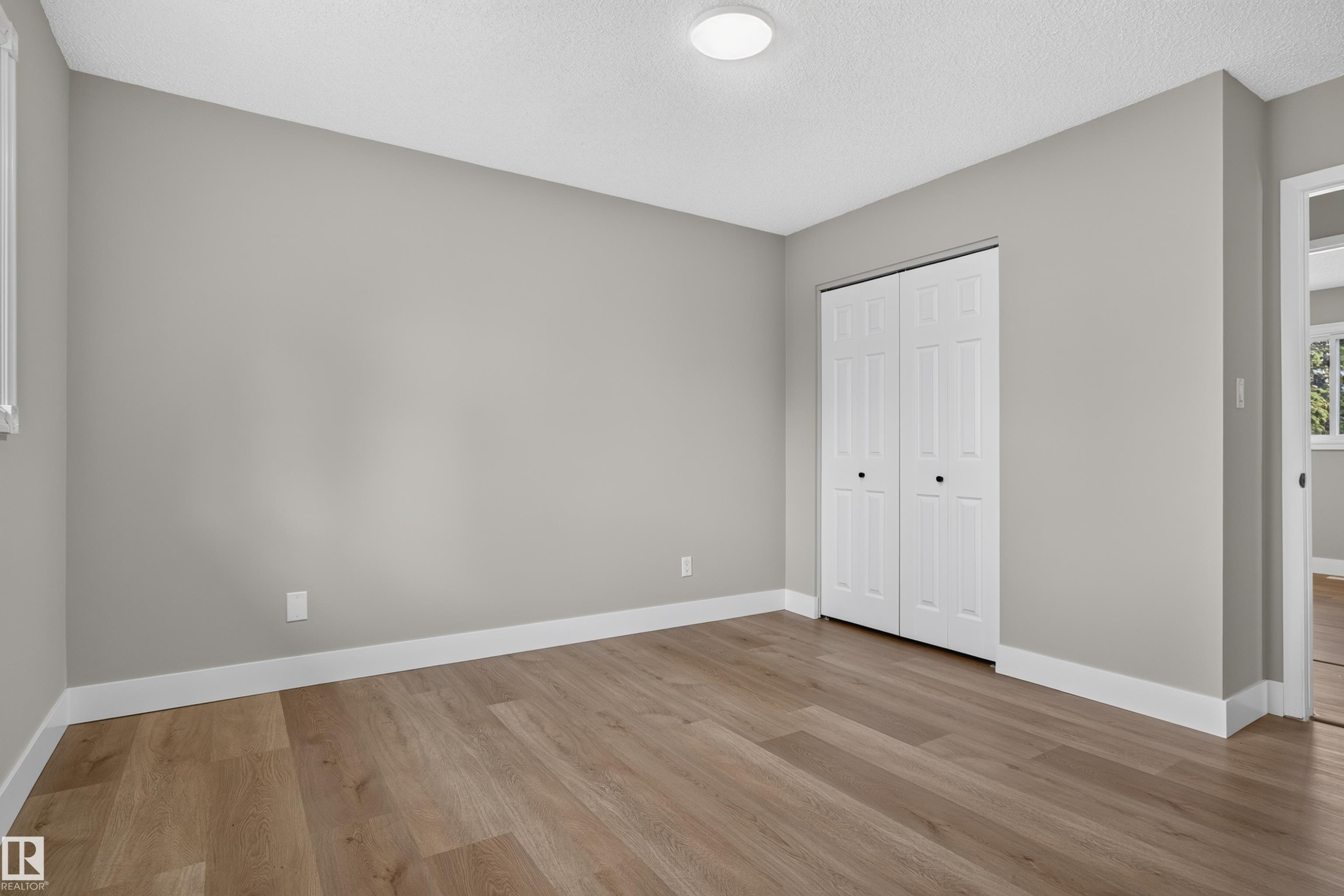Room featuring wood-finish flooring, light gray wall paint, and white baseboards - 33 Brookside Avenue, Spruce Grove, AB