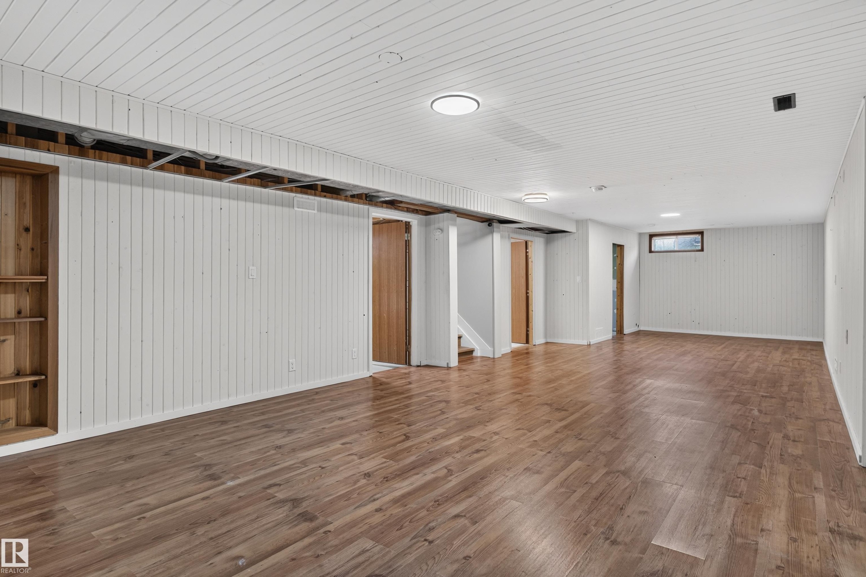 Expansive open-concept room featuring wood-finish flooring, white paneled walls, and a white paneled ceiling - 33 Brookside Avenue, Spruce Grove, AB