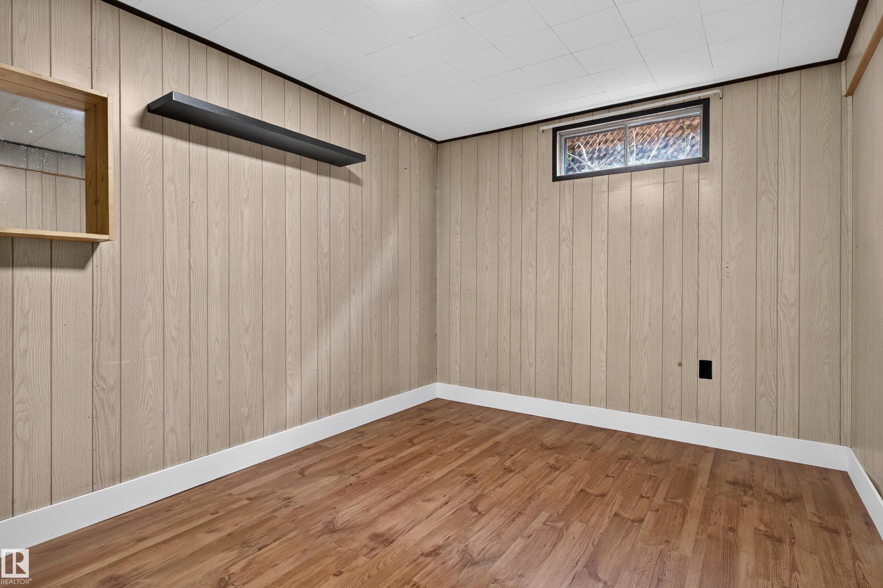 Room featuring wood-finish paneling, wood-finish flooring, and white baseboards - 33 Brookside Avenue, Spruce Grove, AB