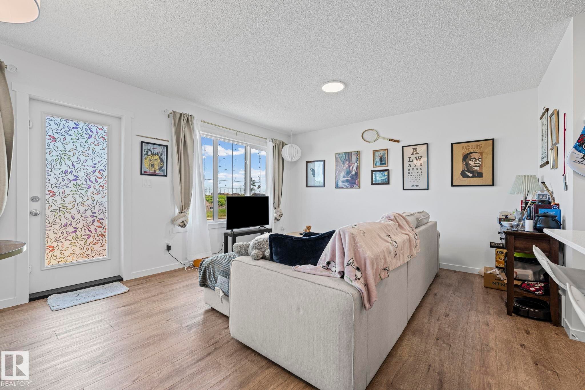 Bright living area featuring wood-finish flooring, white walls, and a white ceiling - 16 19904 31 Avenue, Edmonton, AB