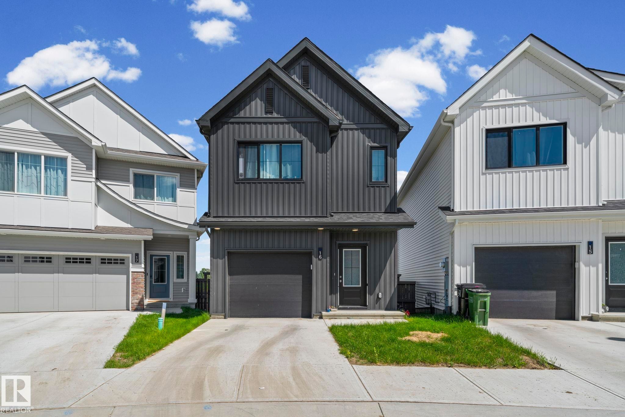 Contemporary home with dark vertical siding, contrasting trim, a single-car garage, and a concrete driveway - 16 19904 31 Avenue, Edmonton, AB
