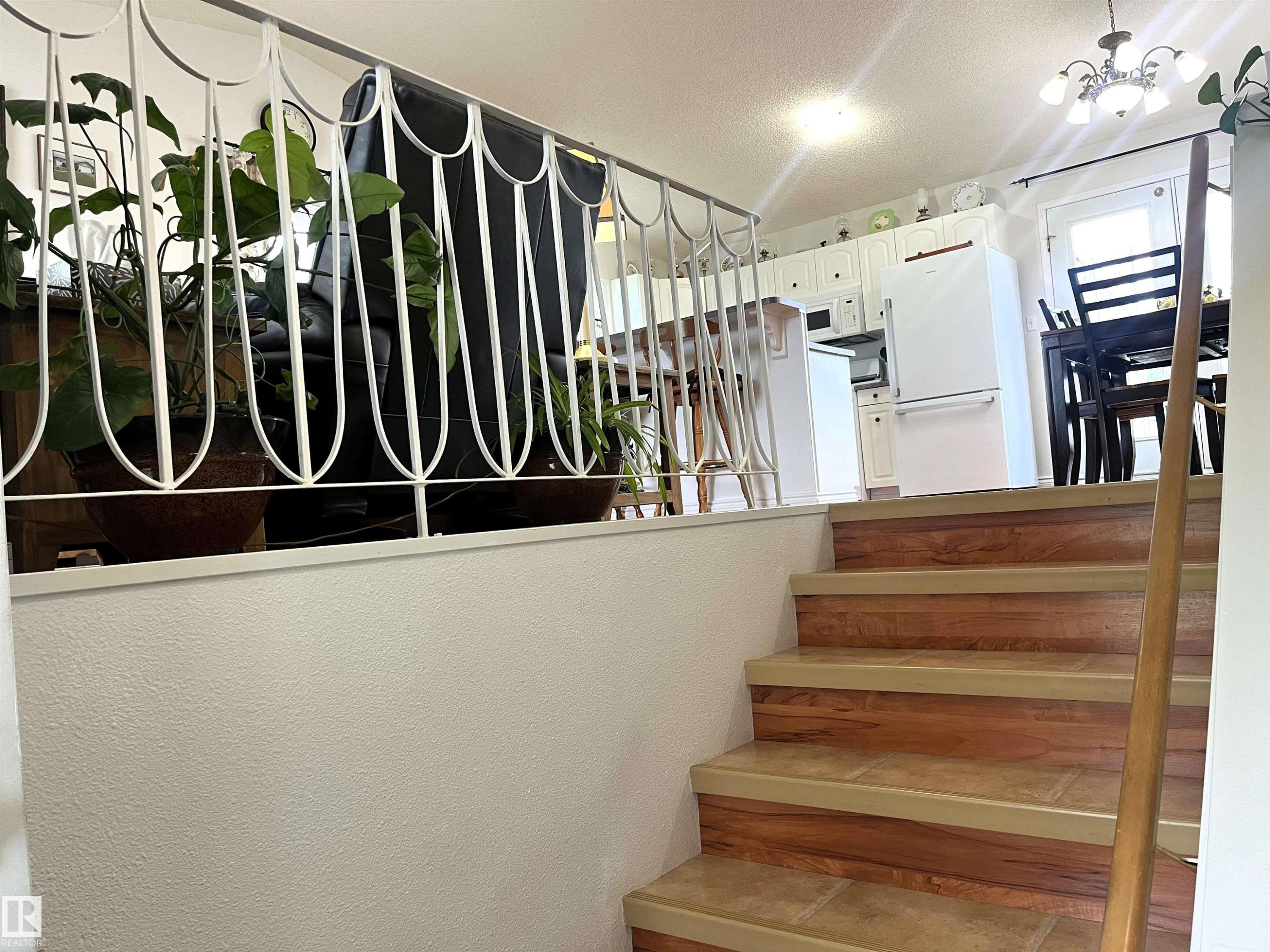 Staircase featuring wood-finish risers and stone-look treads, with a wood handrail - 4914 51 Ave, Entwistle, AB