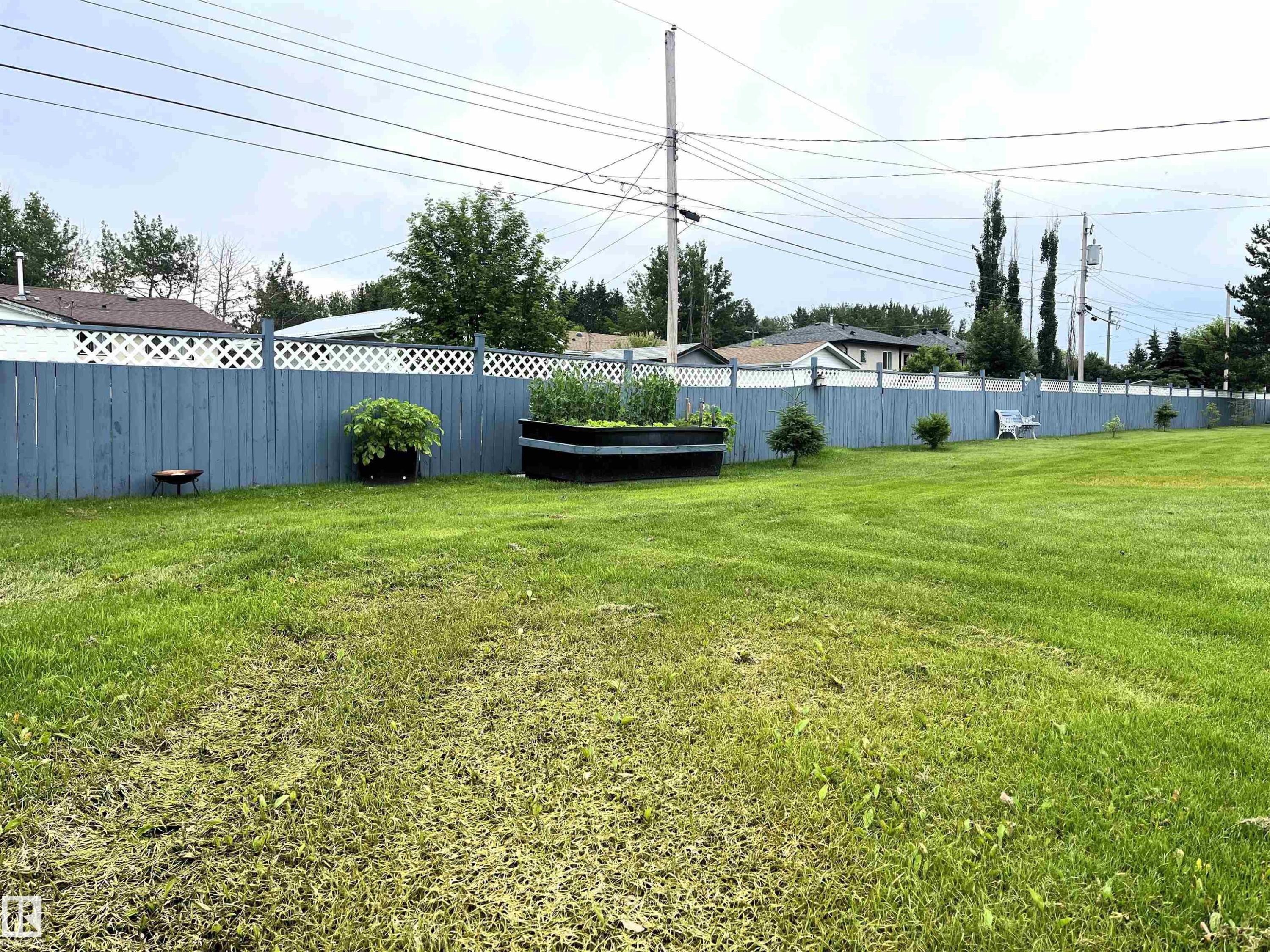 Expansive green lawn featuring a perimeter fence with a lattice top - 4914 51 Ave, Entwistle, AB