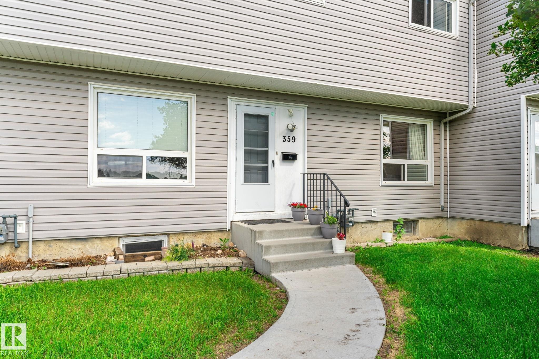 Entryway featuring a white door with storm door, concrete steps with black iron railing, and a curved concrete pathway - 359 Northgate Terrace, Edmonton, AB