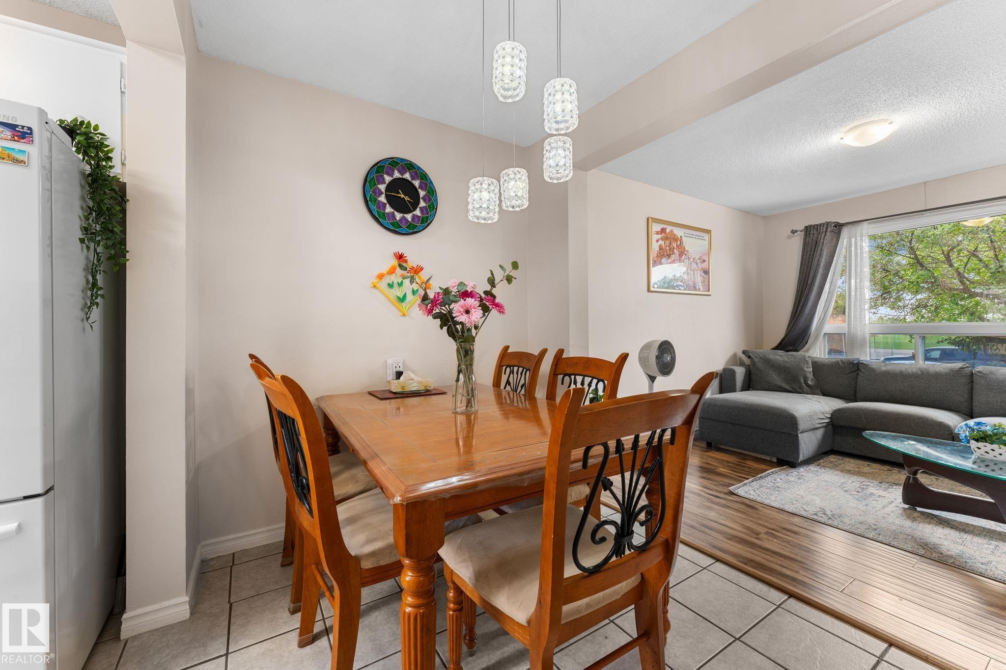 Dining area featuring a contemporary multi-light pendant fixture, tile flooring, and a cased opening - 359 Northgate Terrace, Edmonton, AB
