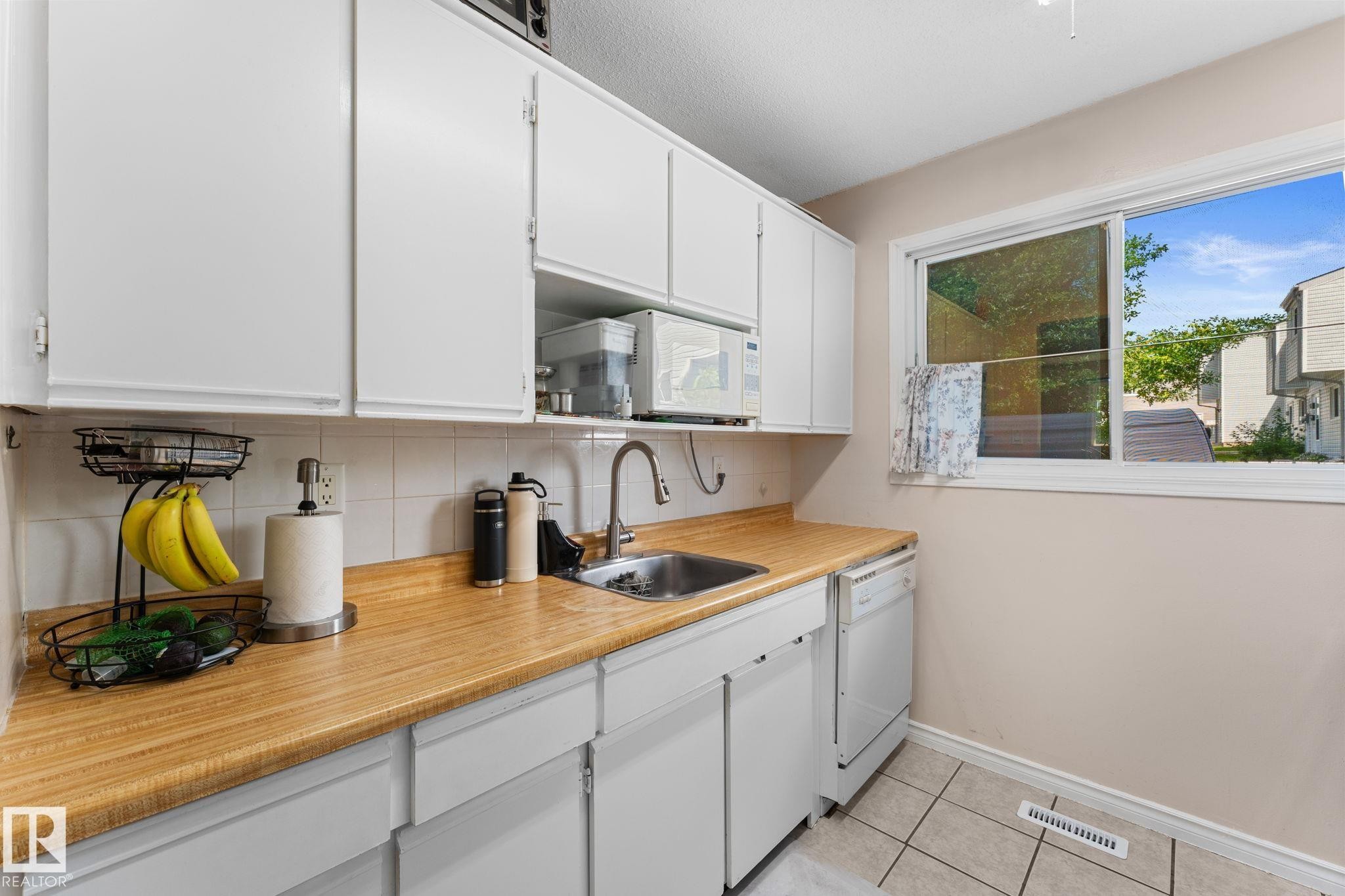 Kitchen featuring white cabinetry, light wood-finish countertops, and a white tile backsplash - 359 Northgate Terrace, Edmonton, AB