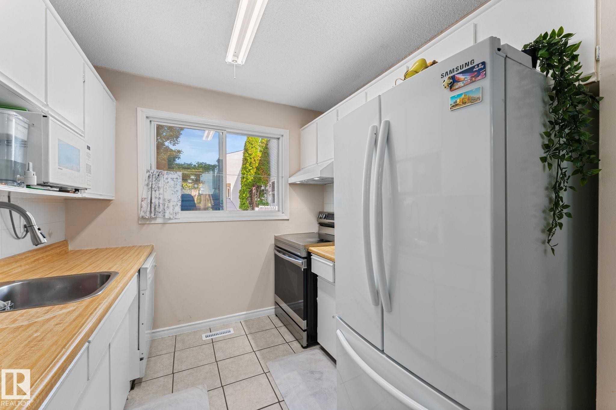 Compact kitchen featuring white cabinetry and wood-finish countertops - 359 Northgate Terrace, Edmonton, AB