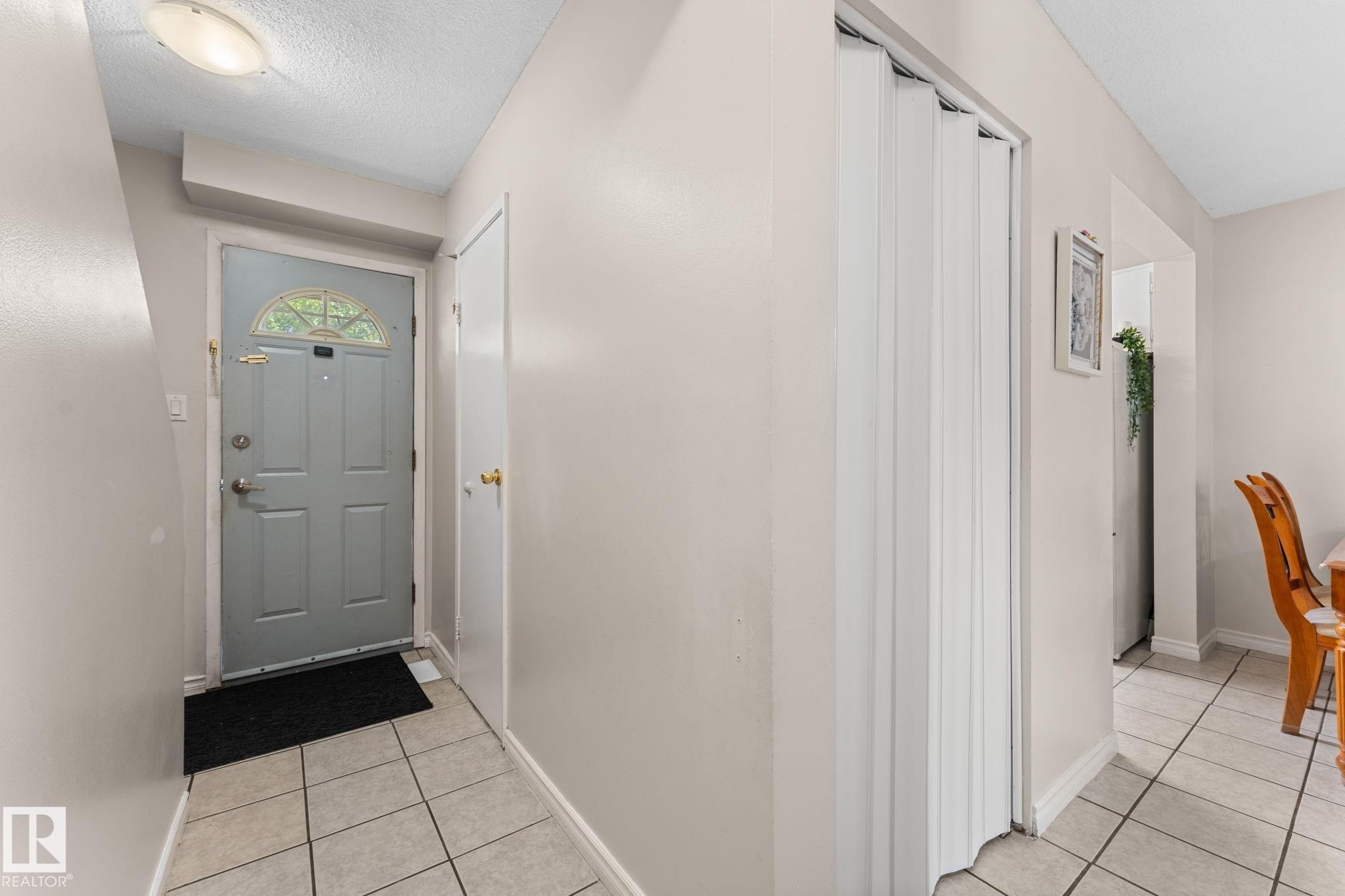 Entryway featuring ceramic tile flooring, a paneled door with an arched transom window, and a flush-mount ceiling light - 359 Northgate Terrace, Edmonton, AB