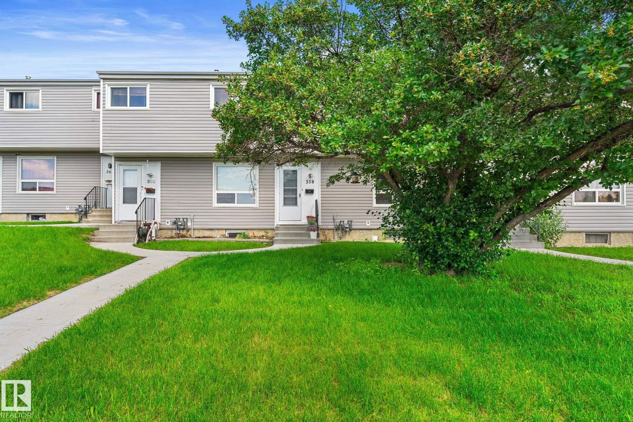 Townhome exterior featuring gray horizontal siding, white trim windows, and individual entry doors - 359 Northgate Terrace, Edmonton, AB