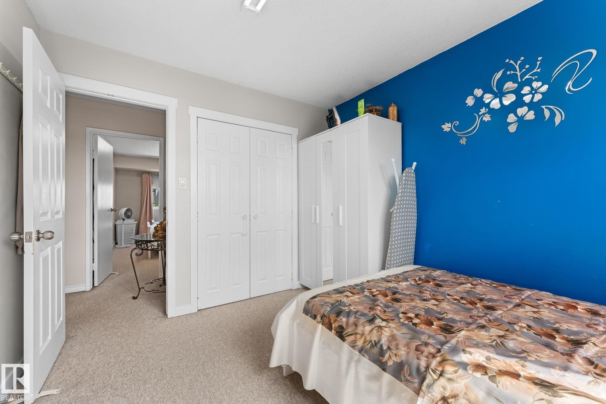Carpeted room featuring a white bi-fold closet and a vibrant accent wall - 359 Northgate Terrace, Edmonton, AB