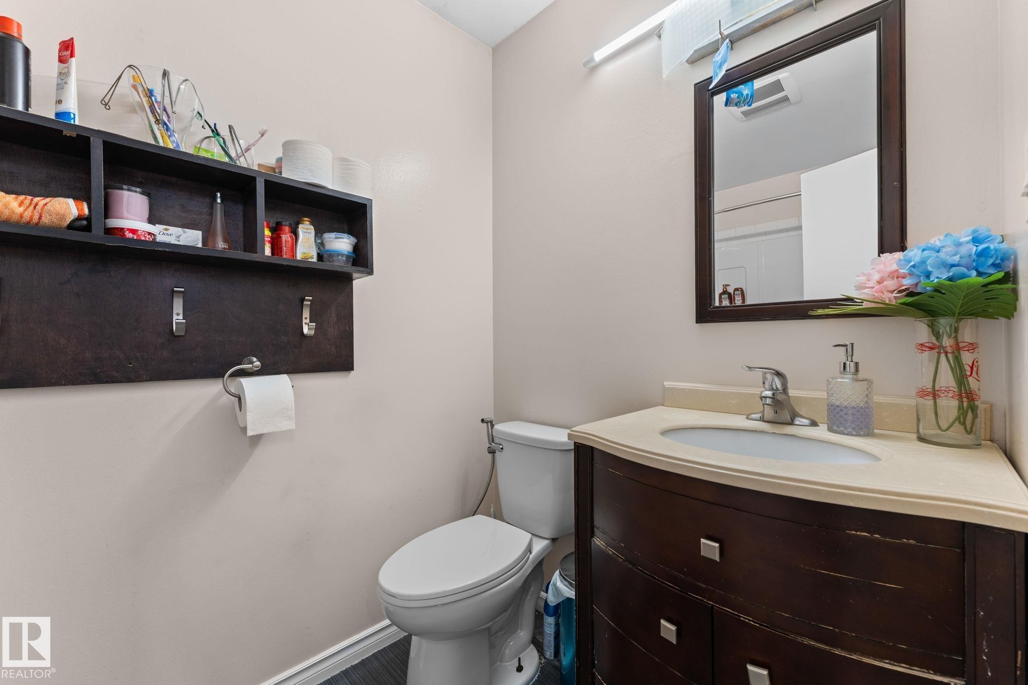 Bathroom featuring a dark wood-finish vanity with a light-toned countertop, an undermount sink, and a framed mirror - 359 Northgate Terrace, Edmonton, AB