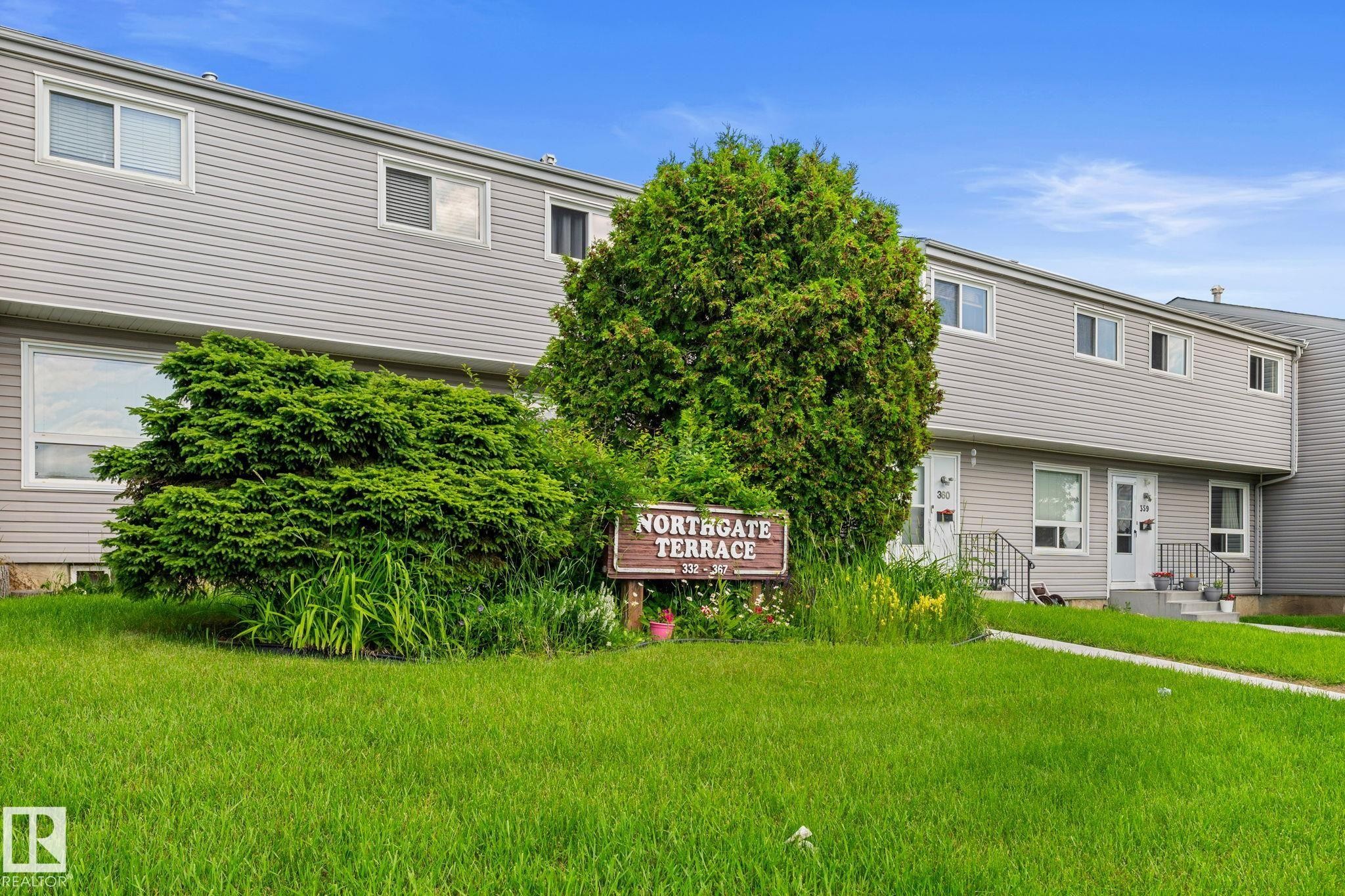 Exterior featuring light gray siding, white window frames, and multiple mature shrubs - 359 Northgate Terrace, Edmonton, AB