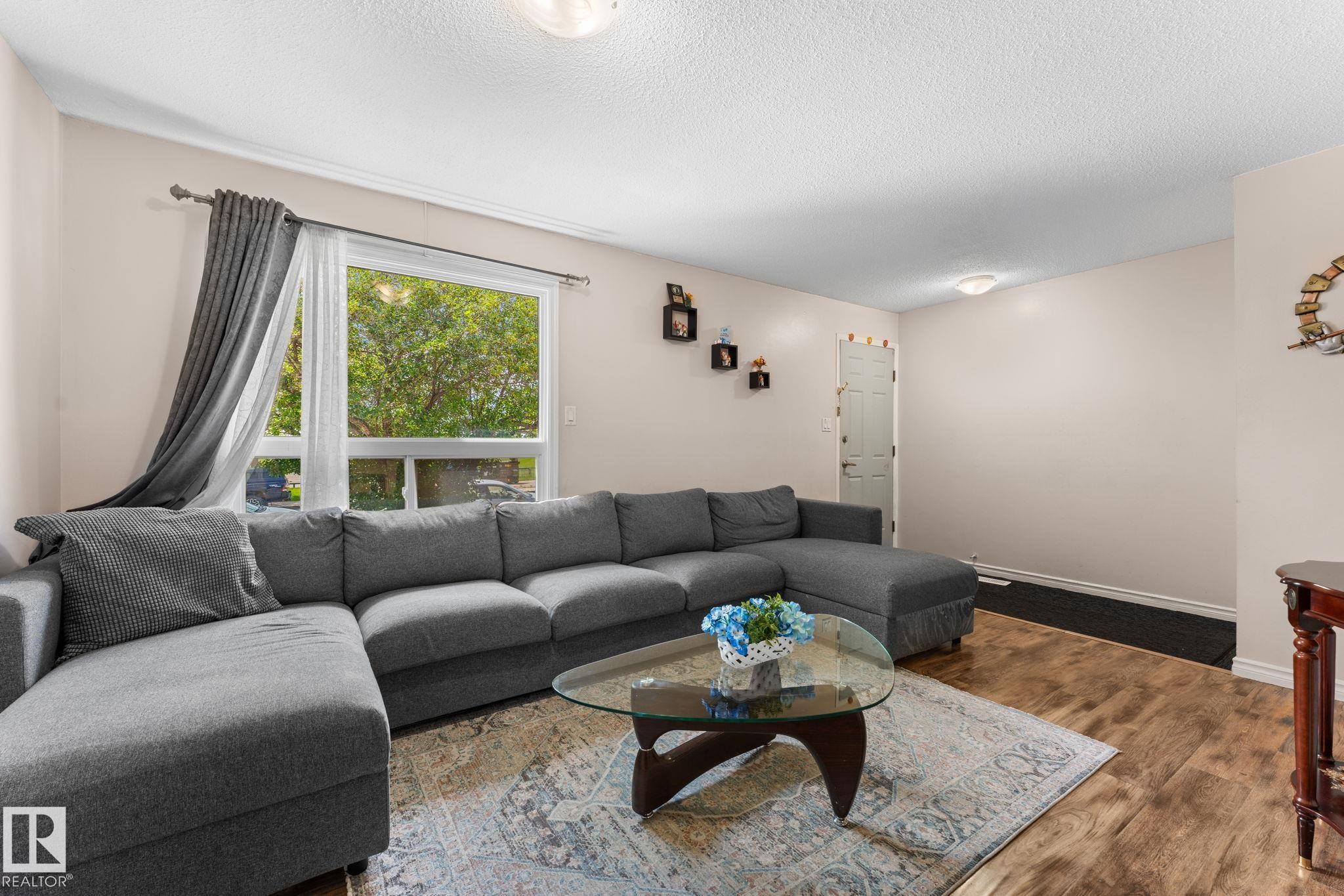 Bright living area featuring a large window, light-toned walls, and wood-finish flooring - 359 Northgate Terrace, Edmonton, AB