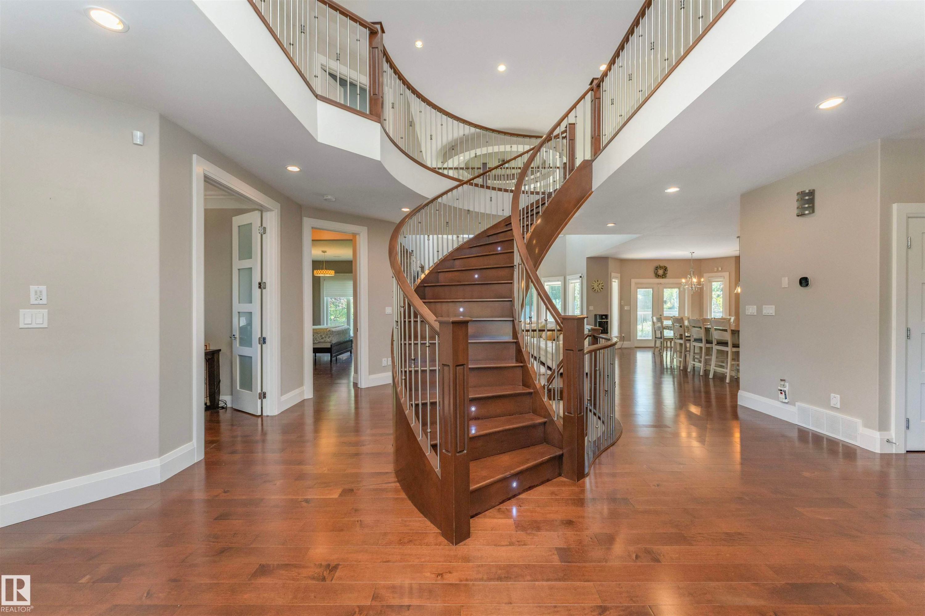 Grand spiral staircase featuring wood treads, white risers, and a wrought iron and wood banister - 3503 Watson Point(E), Edmonton, AB