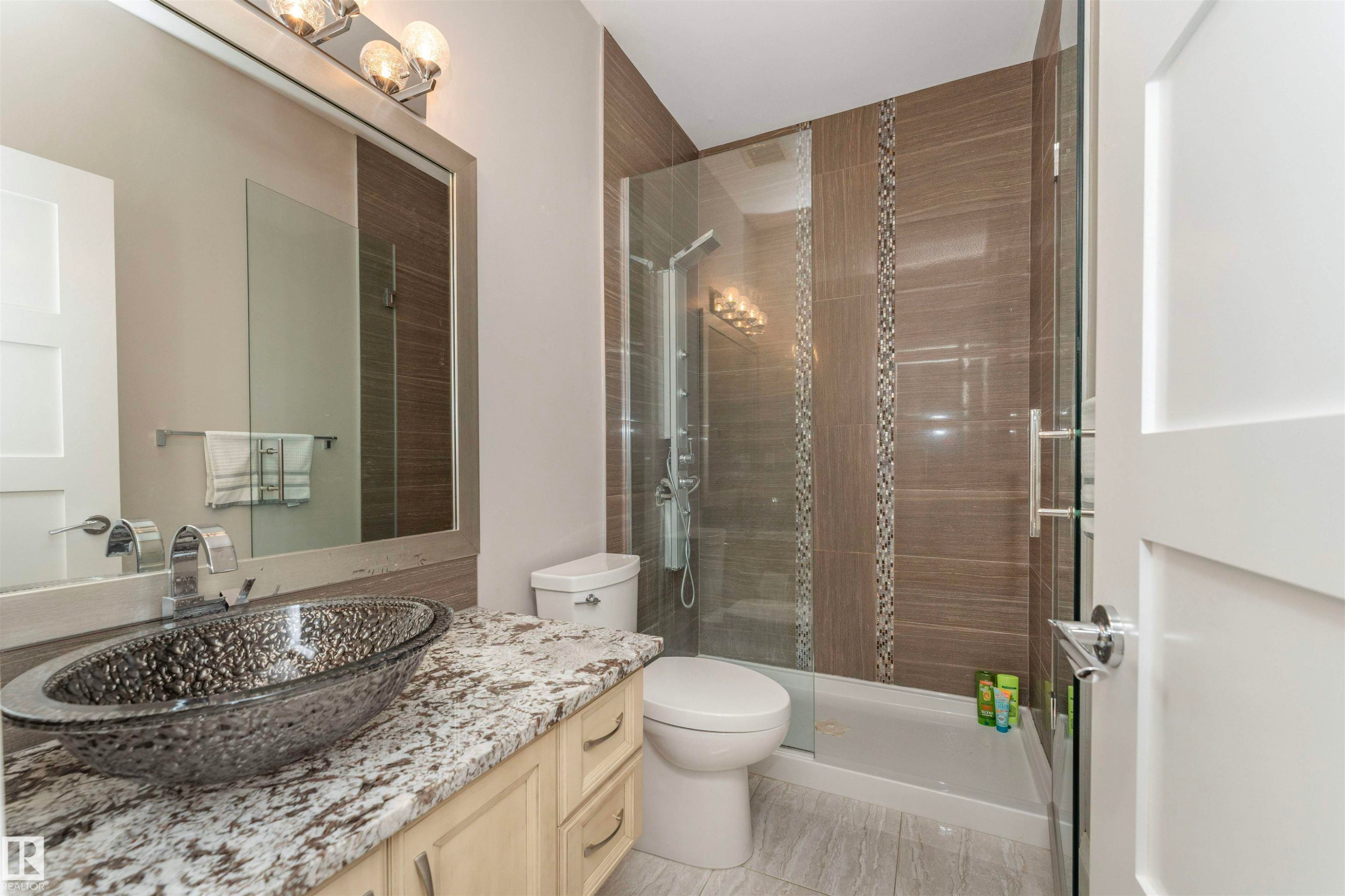 Bathroom featuring a glass vessel sink, speckled countertop, and light wood-finish cabinetry - 3503 Watson Point(E), Edmonton, AB