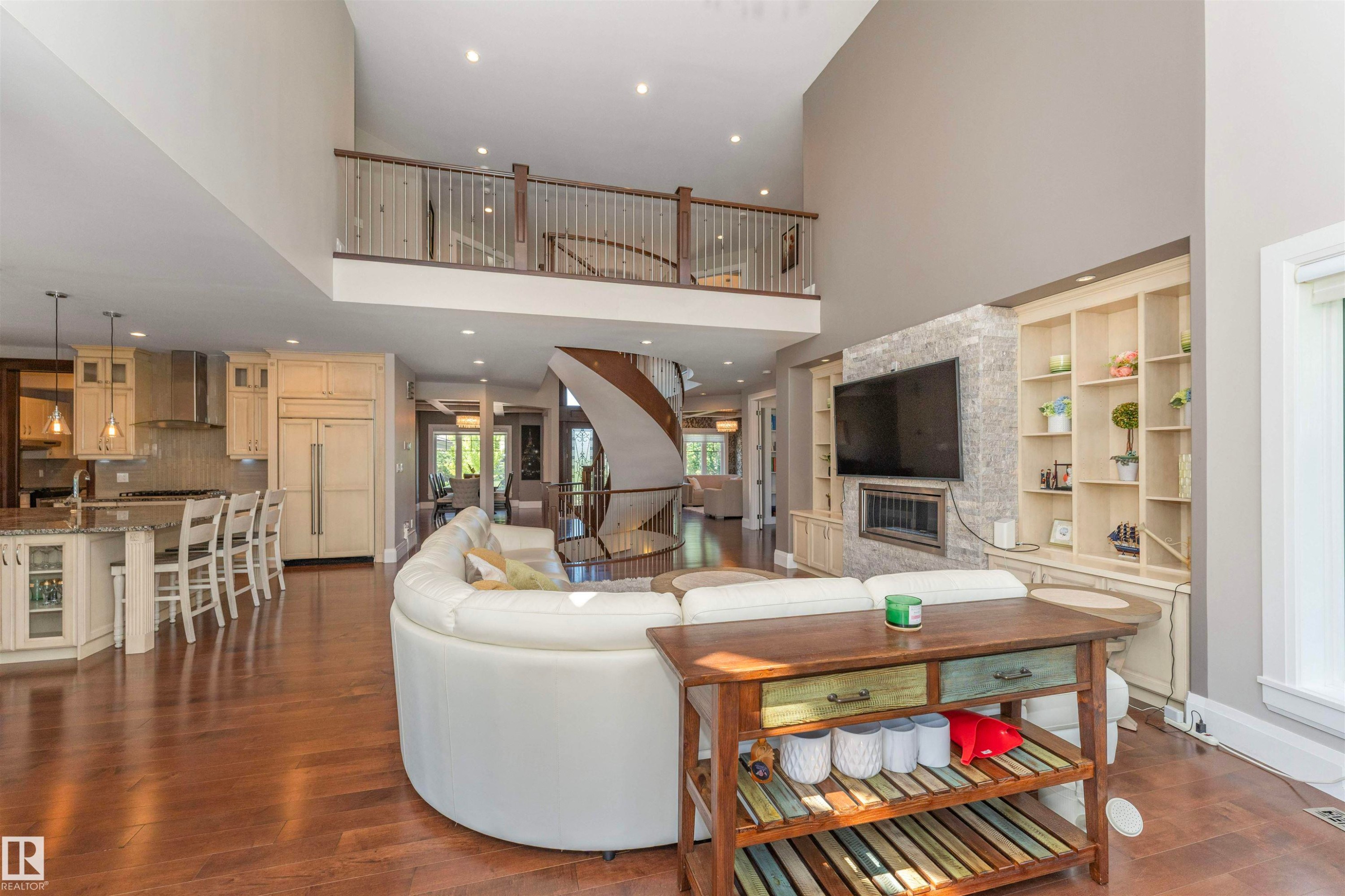 Two-story living area featuring hardwood flooring, a stone-accented fireplace surround, and built-in shelving - 3503 Watson Point(E), Edmonton, AB