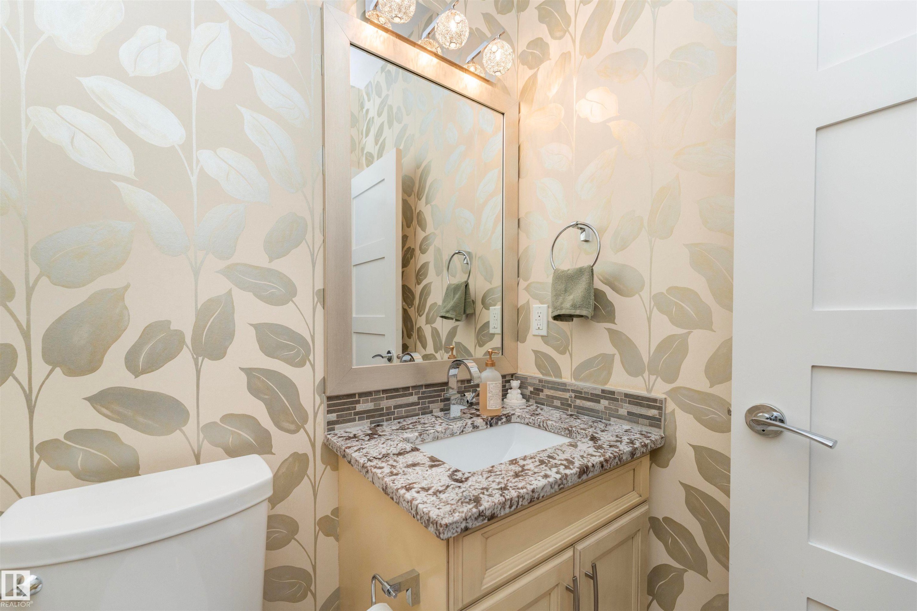 Powder room featuring a single vanity with a granite countertop, undermount sink, and mosaic tile backsplash - 3503 Watson Point(E), Edmonton, AB