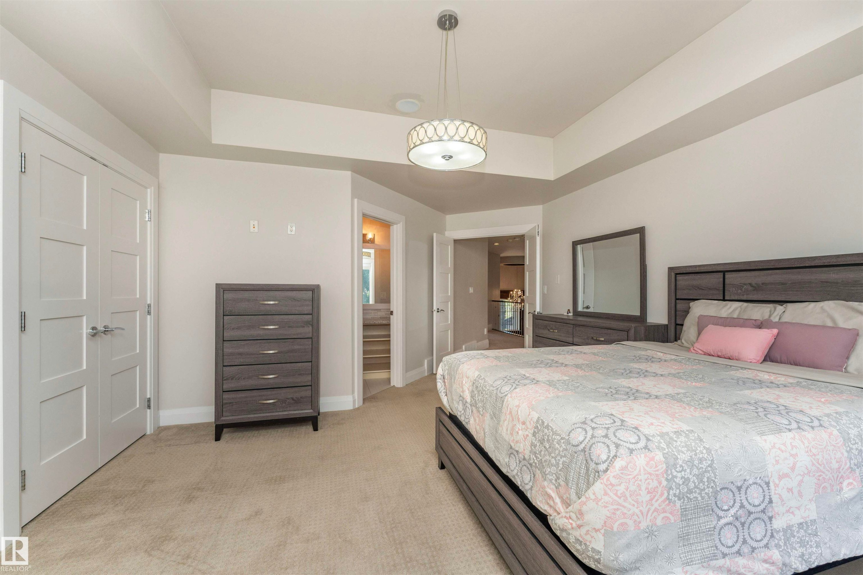 Carpeted bedroom featuring a contemporary pendant light fixture, tray ceiling, and white trim - 3503 Watson Point(E), Edmonton, AB