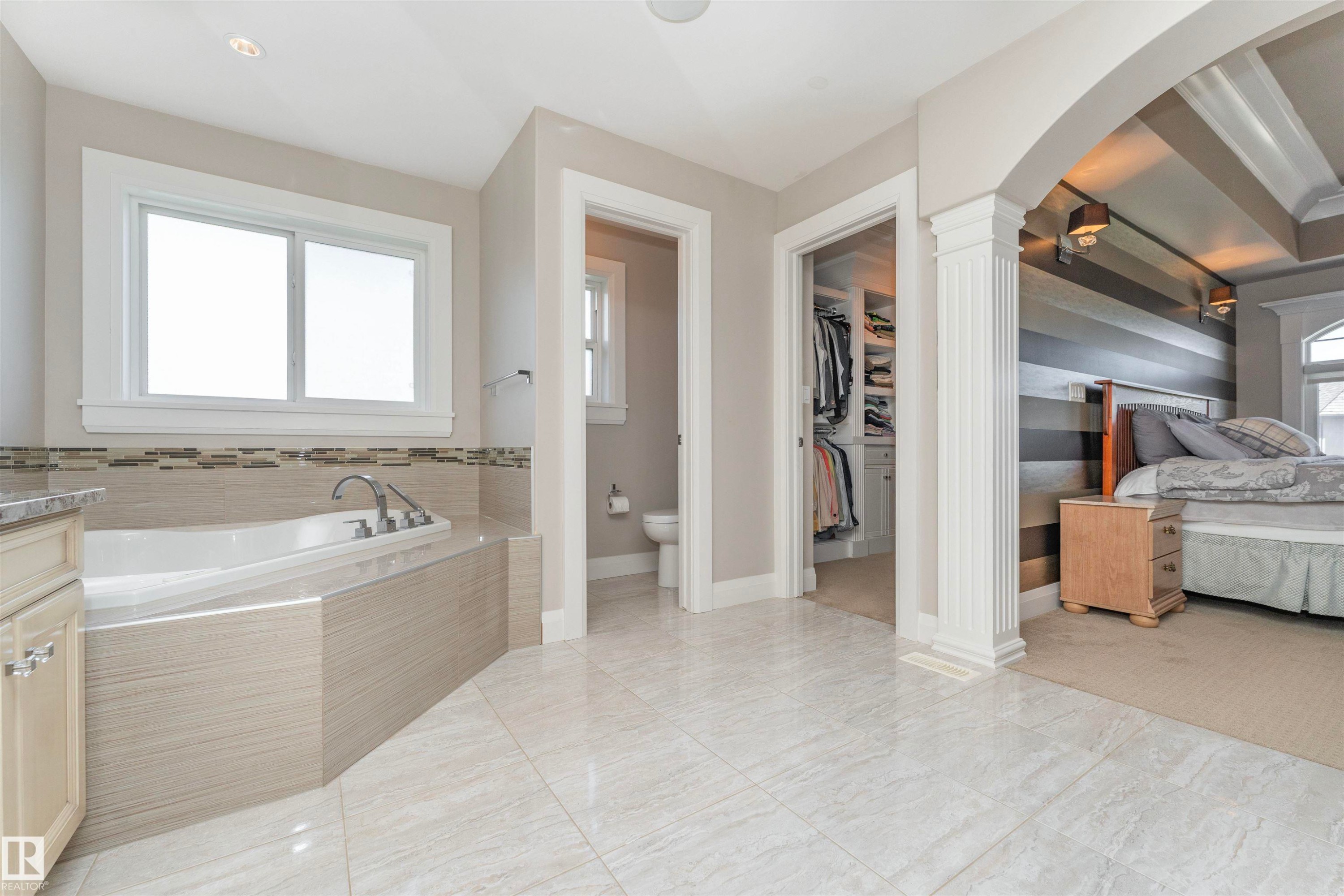 Spacious bathroom featuring a built-in tub with tile surround, large format tile flooring, and light-toned cabinetry - 3503 Watson Point(E), Edmonton, AB