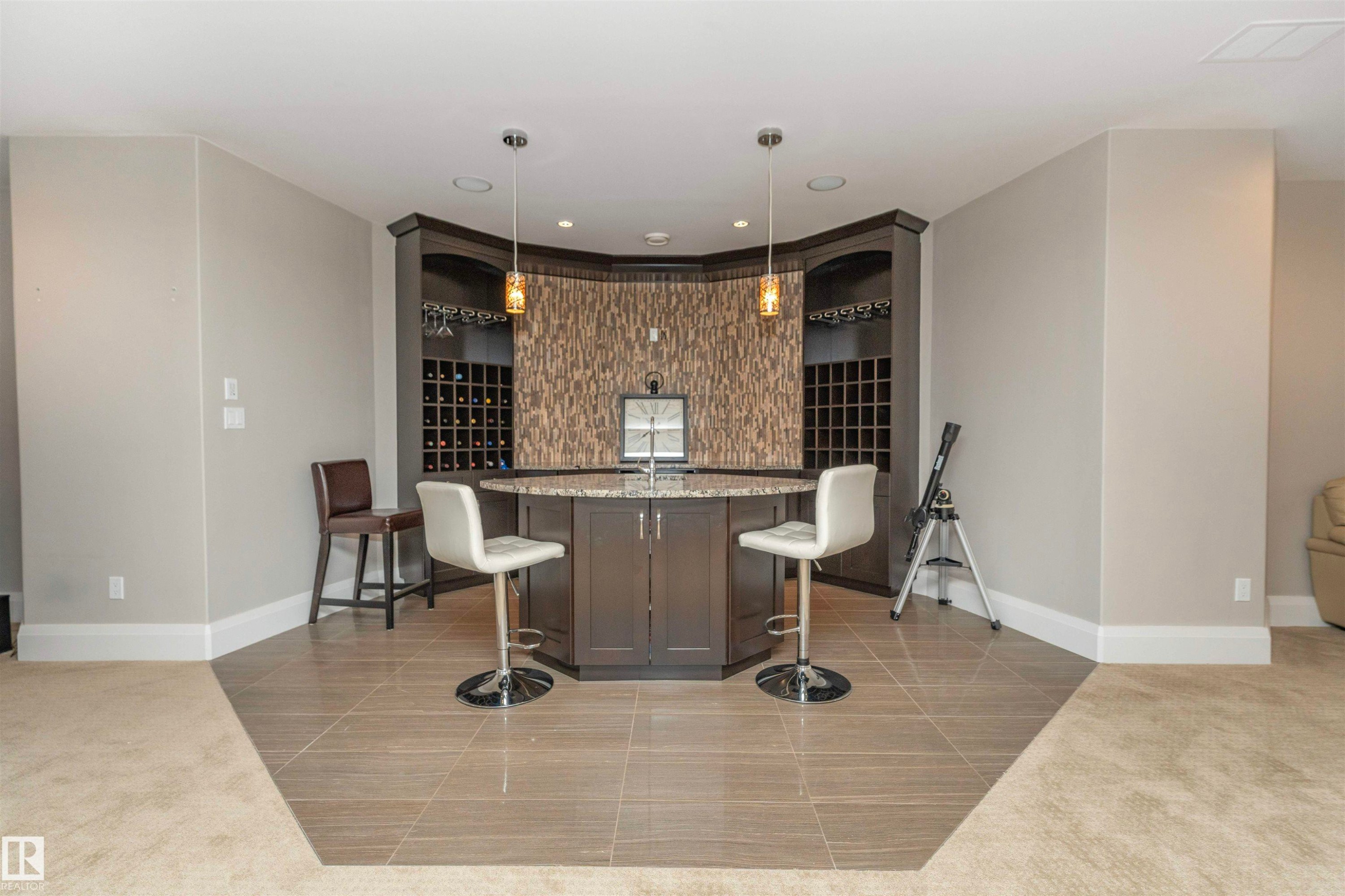 Custom built-in wet bar featuring dark wood cabinetry, integrated wine storage, and a textured backsplash - 3503 Watson Point(E), Edmonton, AB