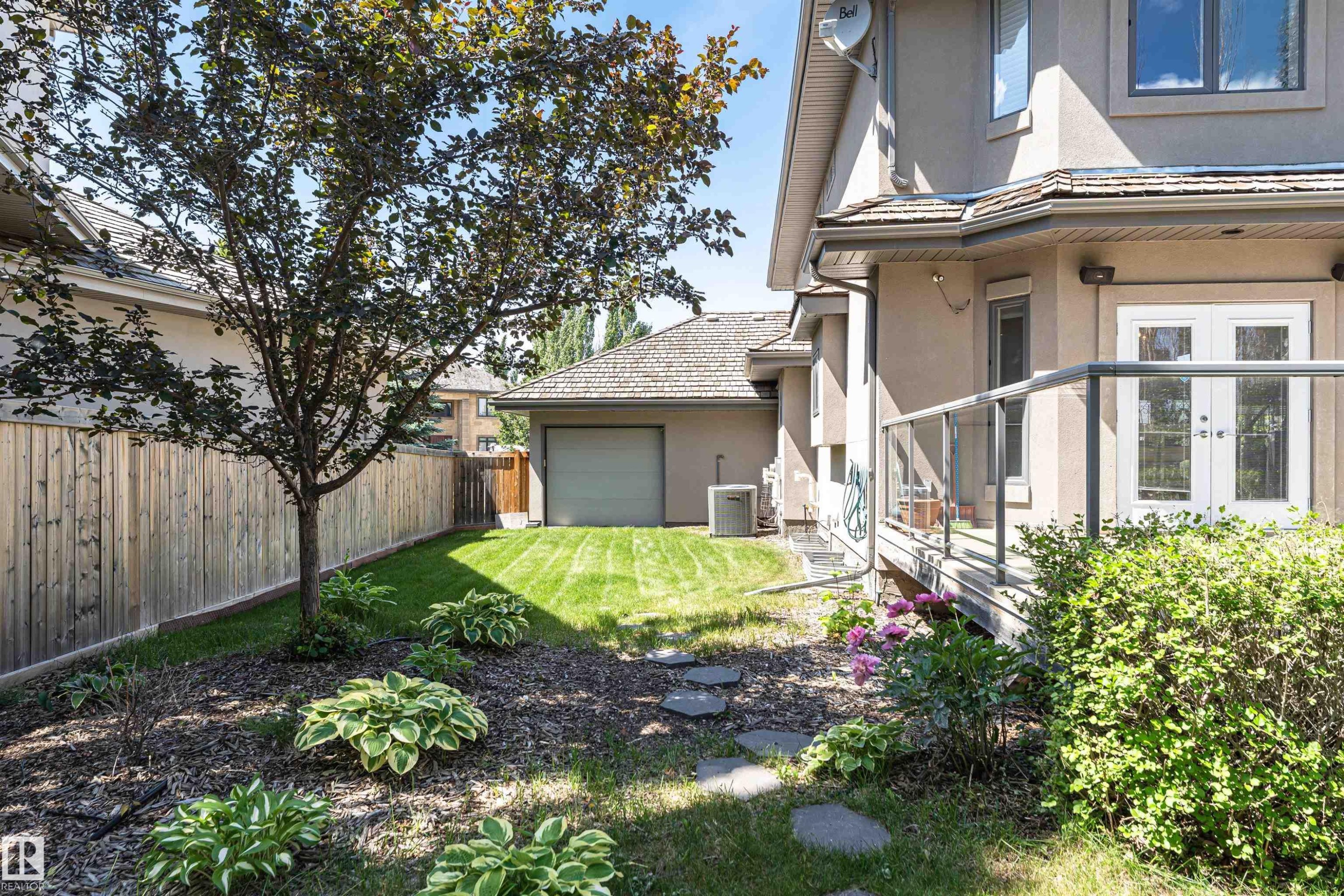 Expansive backyard featuring a manicured lawn, established tree, and stepping stones - 3503 Watson Point(E), Edmonton, AB
