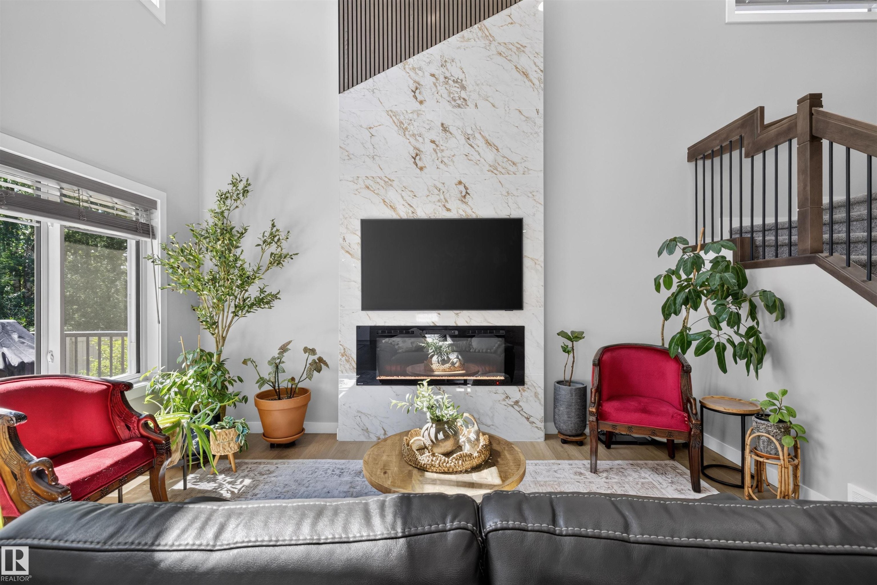 Living area featuring a floor-to-ceiling fireplace with marble-look surround and integrated linear fireplace - 1573 Esaiw Place Nw, Edmonton, AB