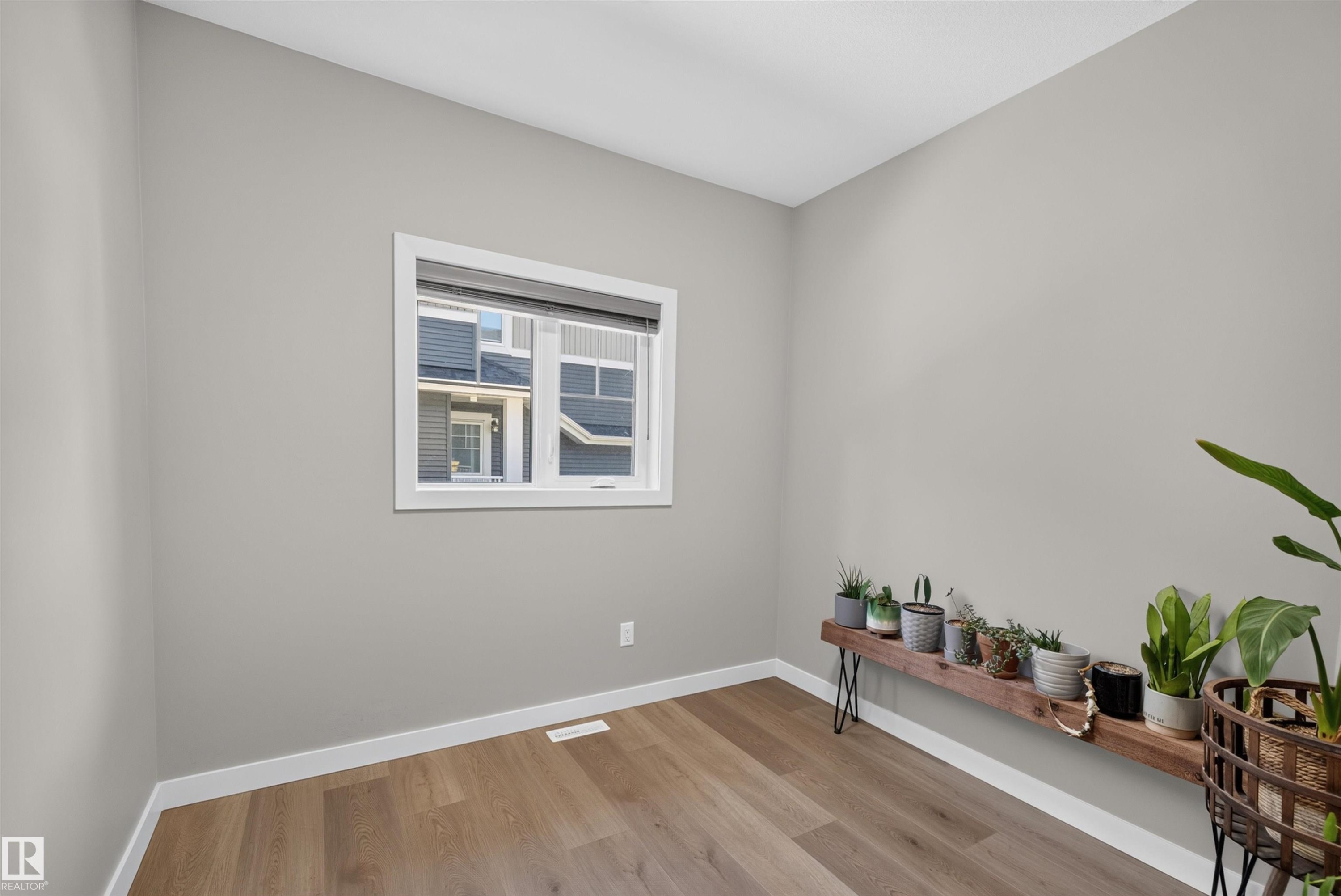 Room featuring light wood-finish flooring, neutral gray wall paint, and white baseboards - 1573 Esaiw Place Nw, Edmonton, AB