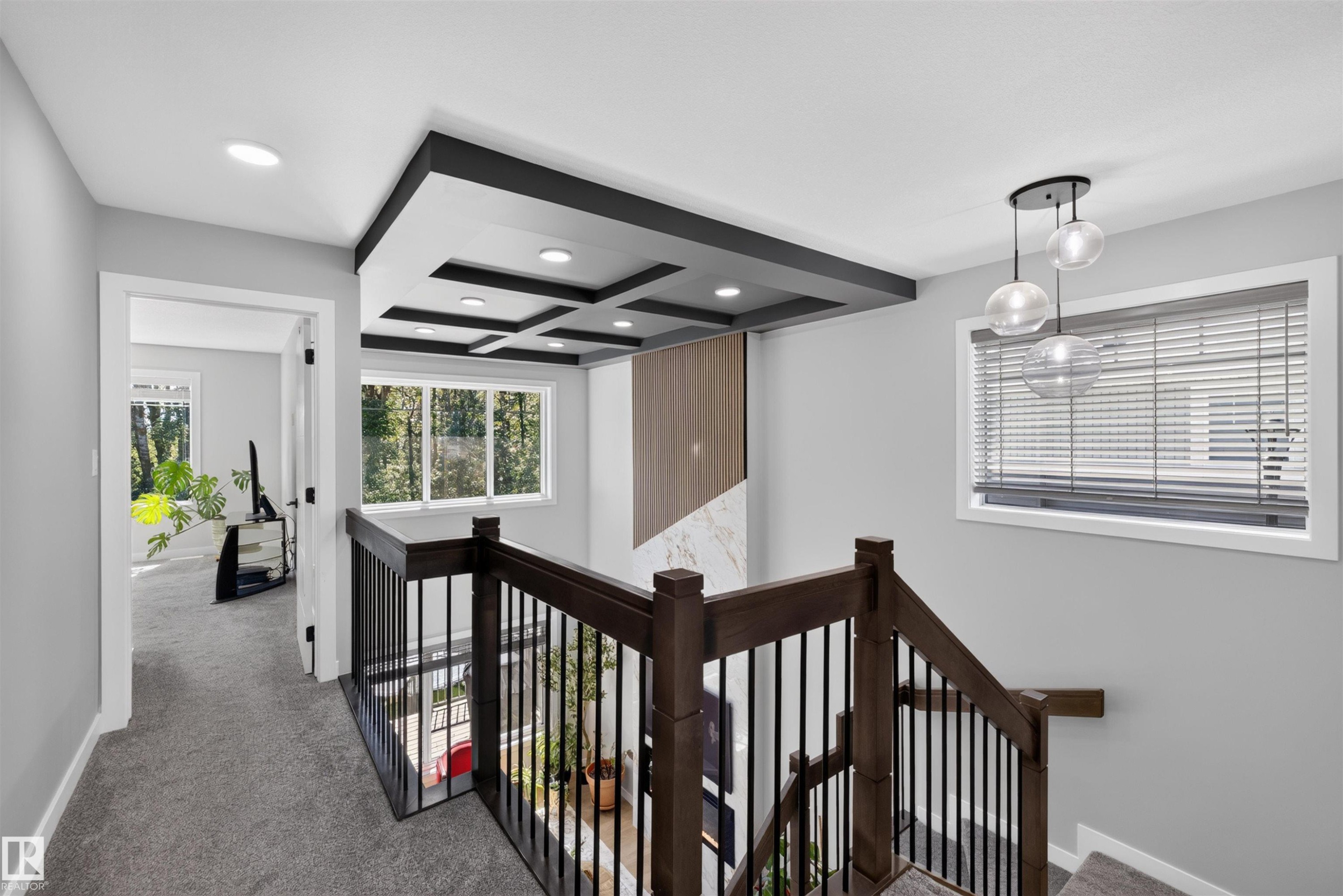 Upper landing featuring a coffered ceiling with recessed lighting, dark wood railing with black metal spindles, and a multi-globe pendant light - 1573 Esaiw Place Nw, Edmonton, AB