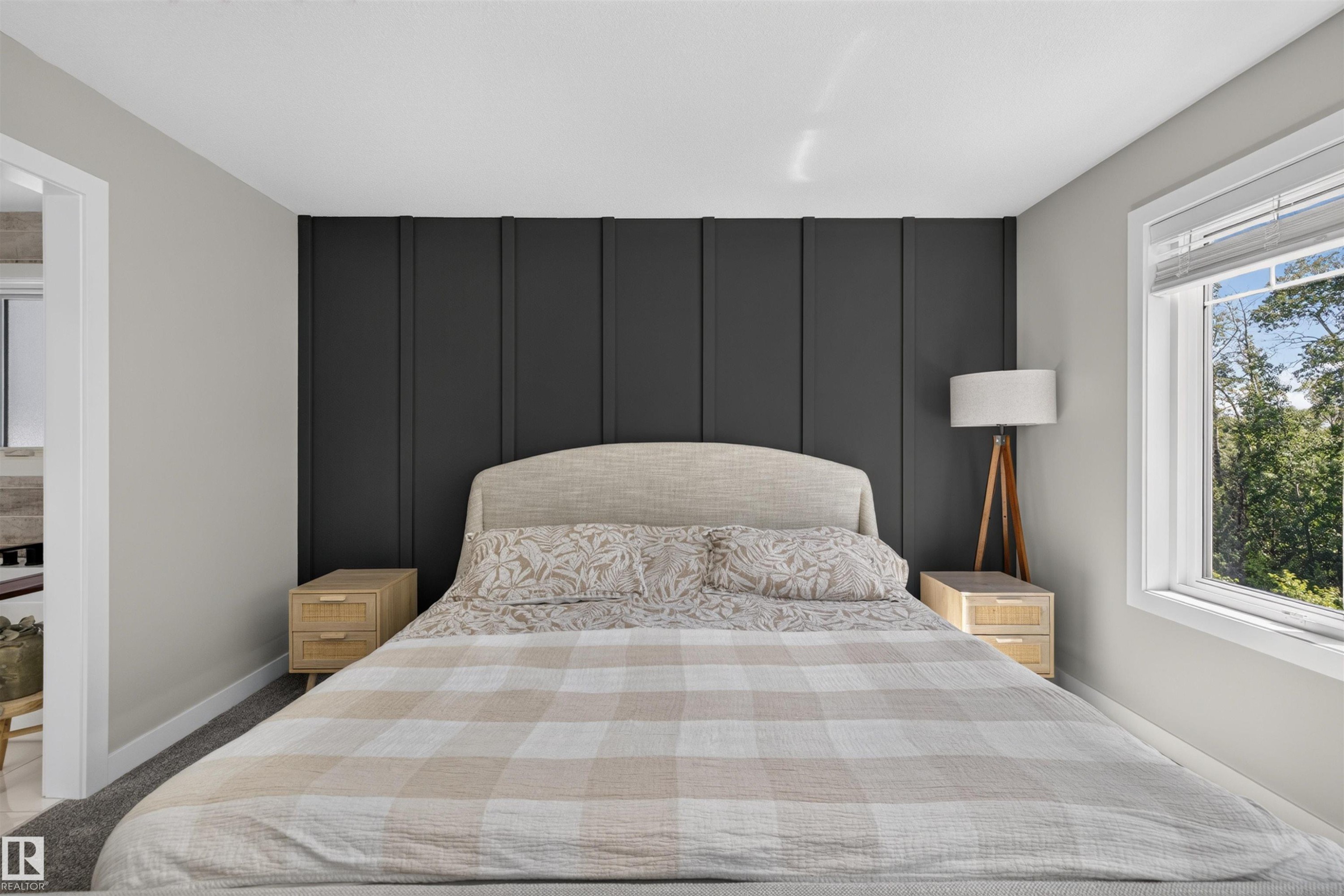 Bedroom featuring a dark accent wall with vertical paneling, a large window with white trim, and light gray wall paint - 1573 Esaiw Place Nw, Edmonton, AB