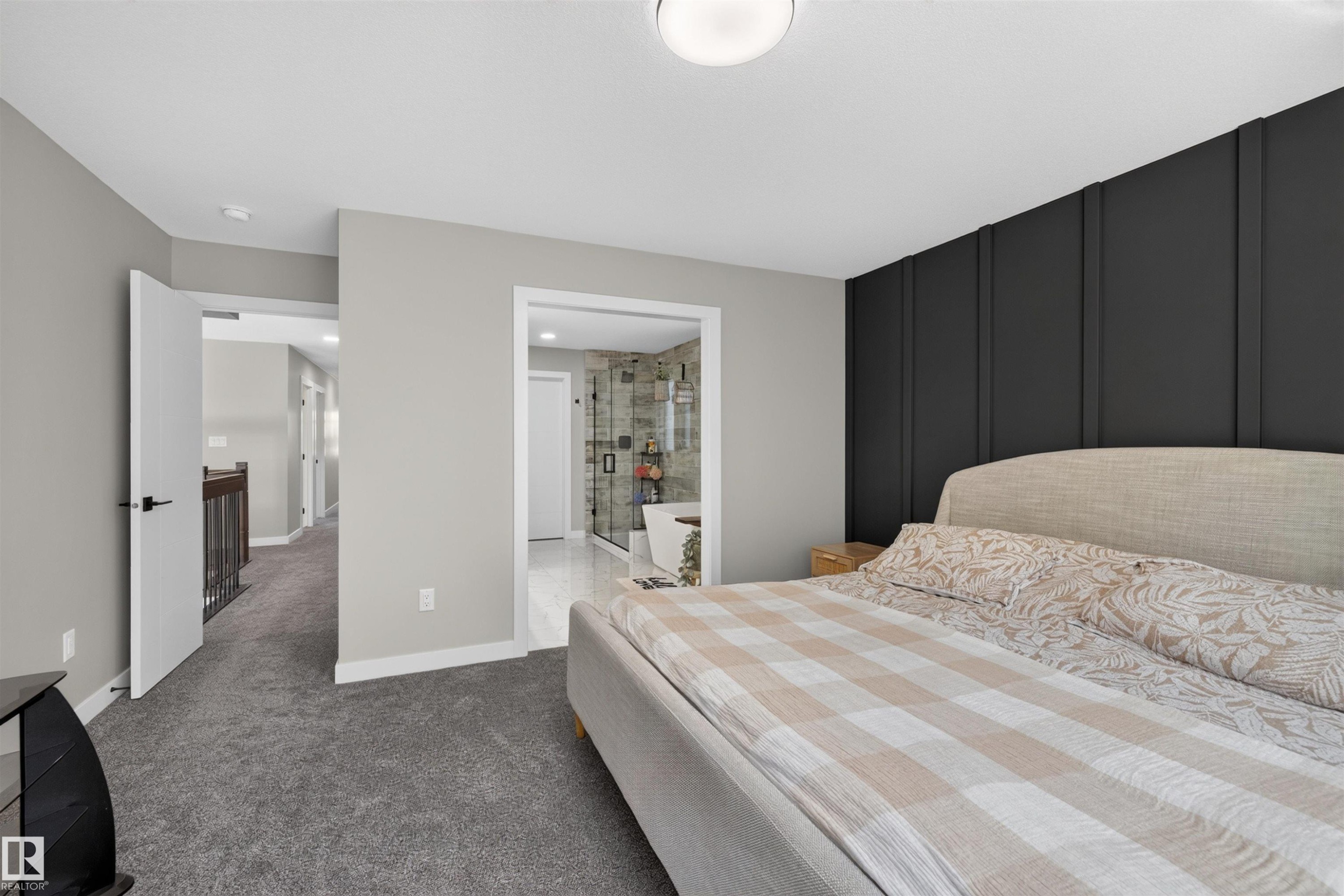 Bedroom featuring plush gray carpeting and a prominent dark accent wall with vertical paneling - 1573 Esaiw Place Nw, Edmonton, AB