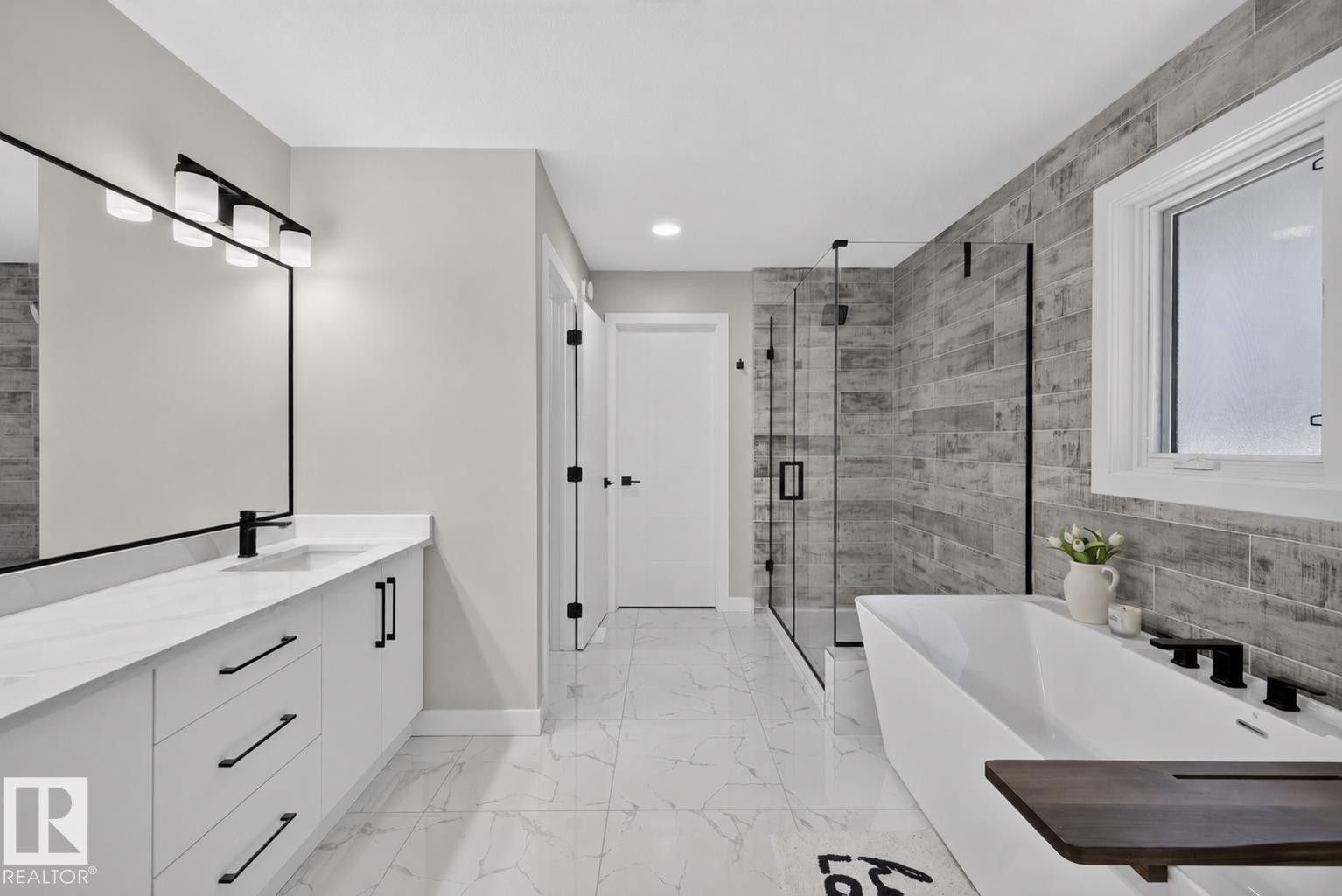 Contemporary bathroom featuring a freestanding soaking tub with matte black fixtures, a glass-enclosed shower, a double vanity with quartz countertops, and marble-look floor tiling - 1573 Esaiw Place Nw, Edmonton, AB