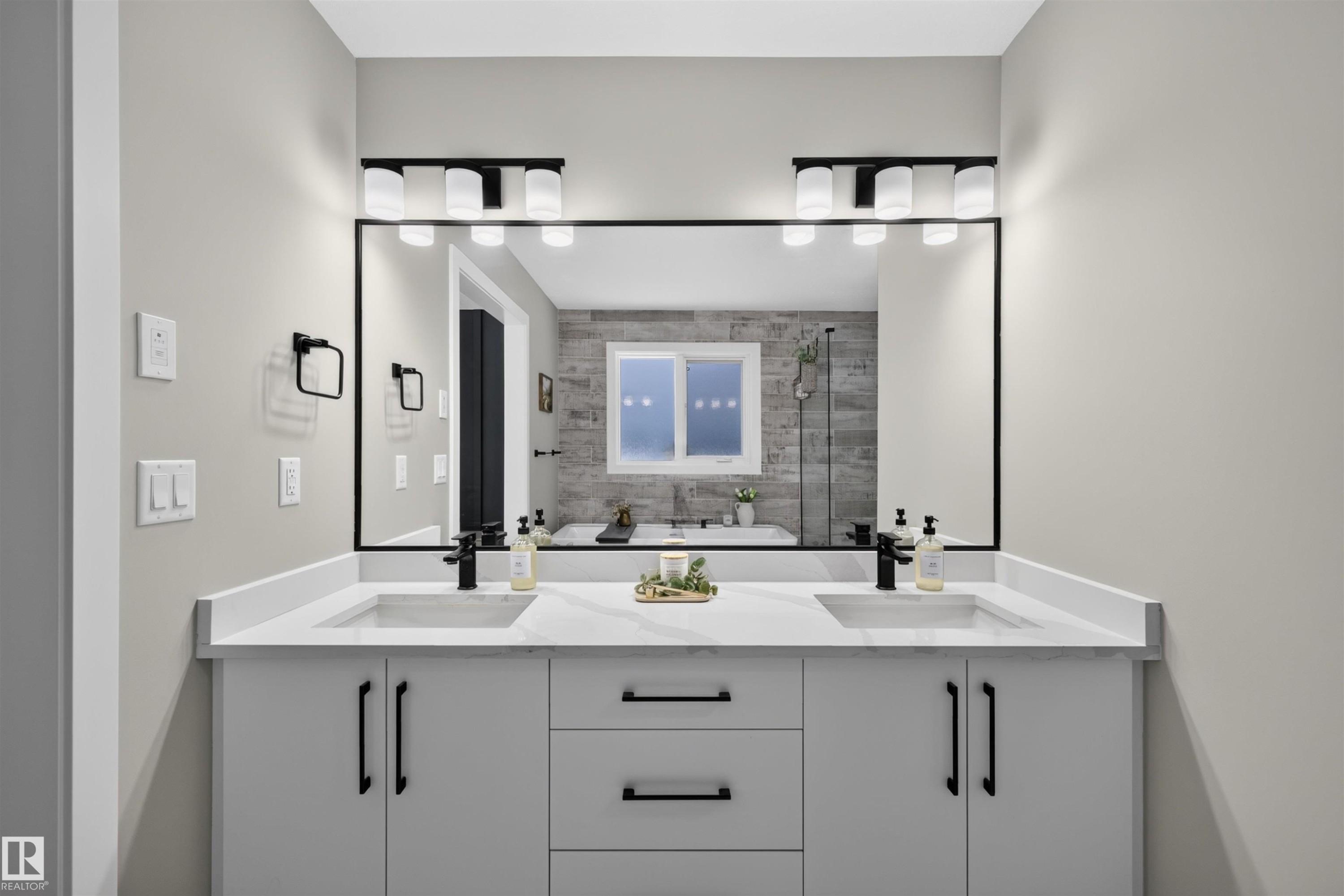 Dual vanity with white cabinetry and integrated sinks, complemented by matte black fixtures and hardware - 1573 Esaiw Place Nw, Edmonton, AB
