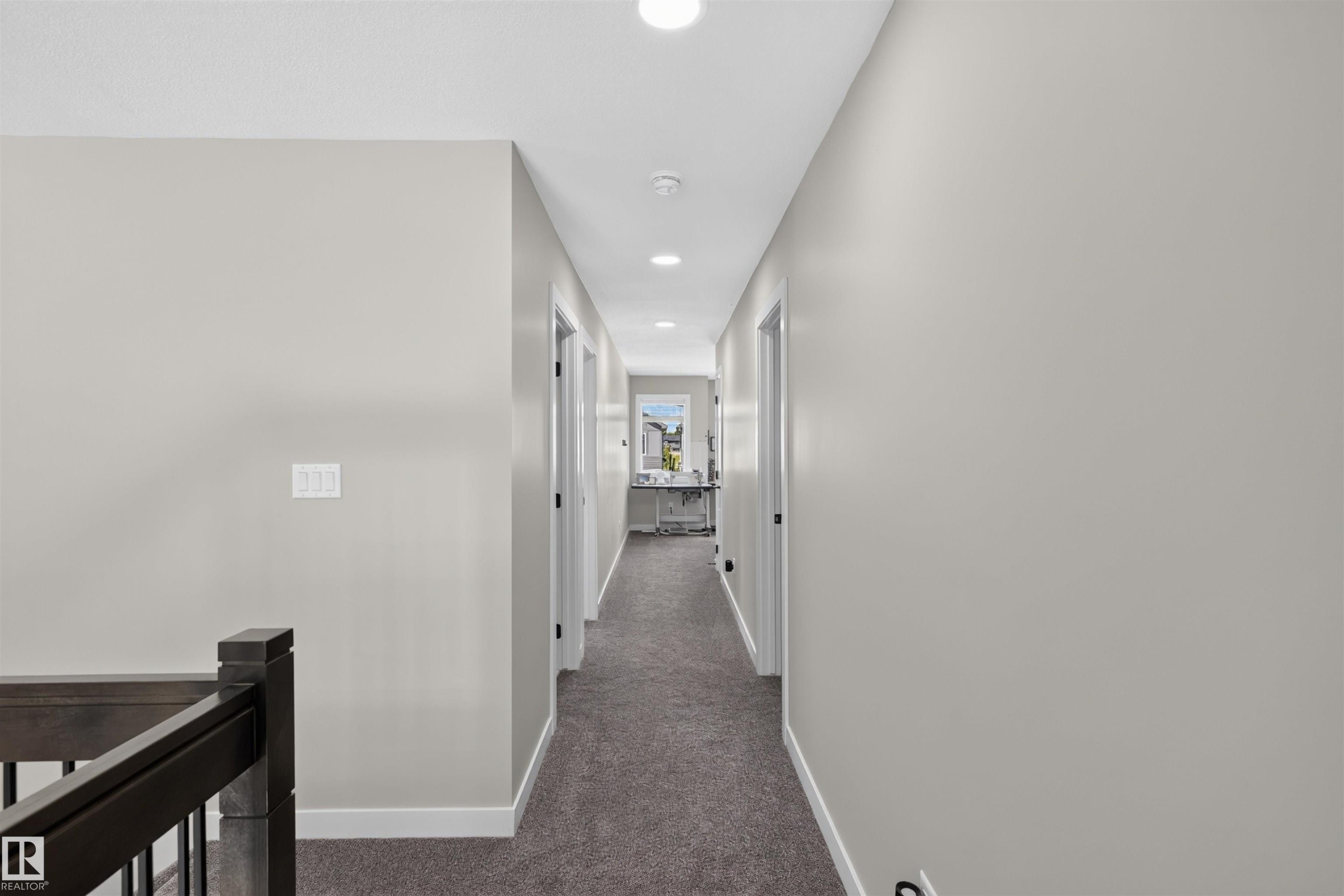 Hallway featuring recessed lighting, light gray painted walls, white trim, and dark gray carpet flooring - 1573 Esaiw Place Nw, Edmonton, AB