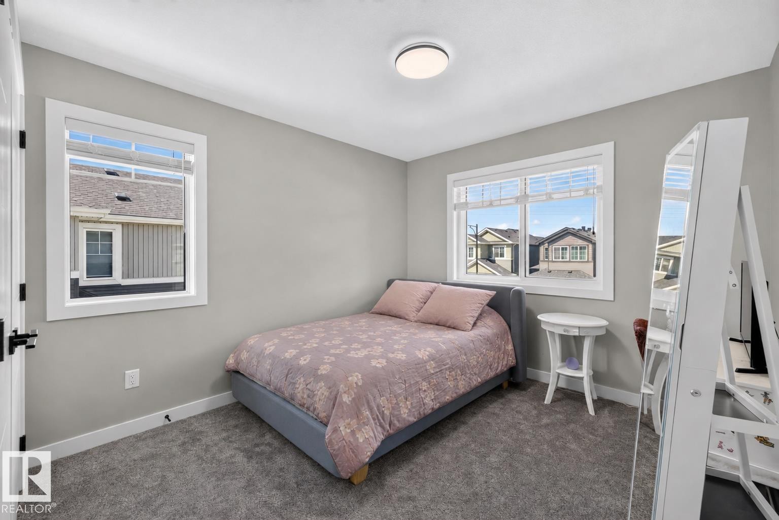 Neutral-toned room featuring a large window, a smaller window, and gray carpeting - 1573 Esaiw Place Nw, Edmonton, AB