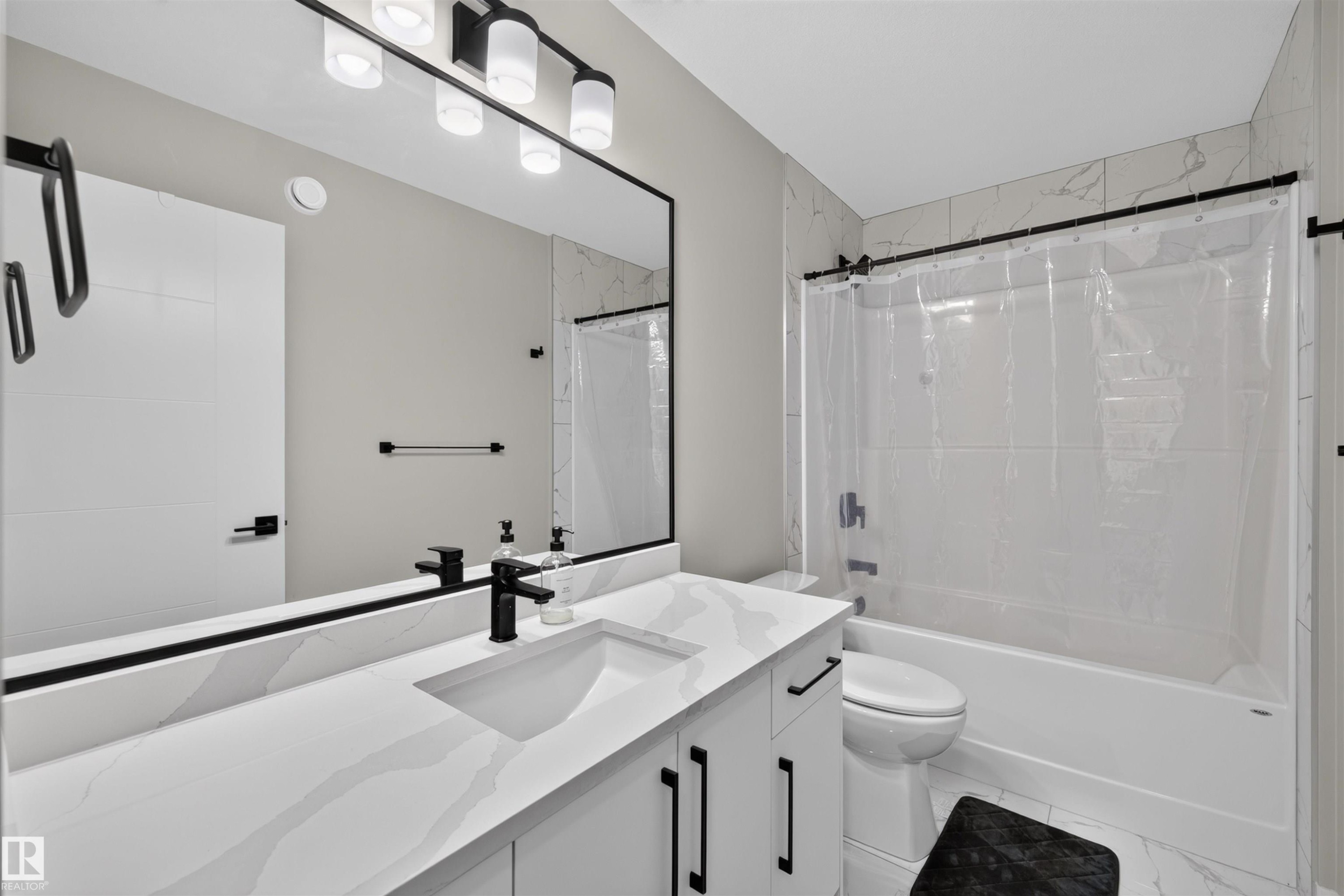 Modern bathroom featuring a single vanity with integrated sink, a white countertop with subtle veining, and matte black hardware - 1573 Esaiw Place Nw, Edmonton, AB