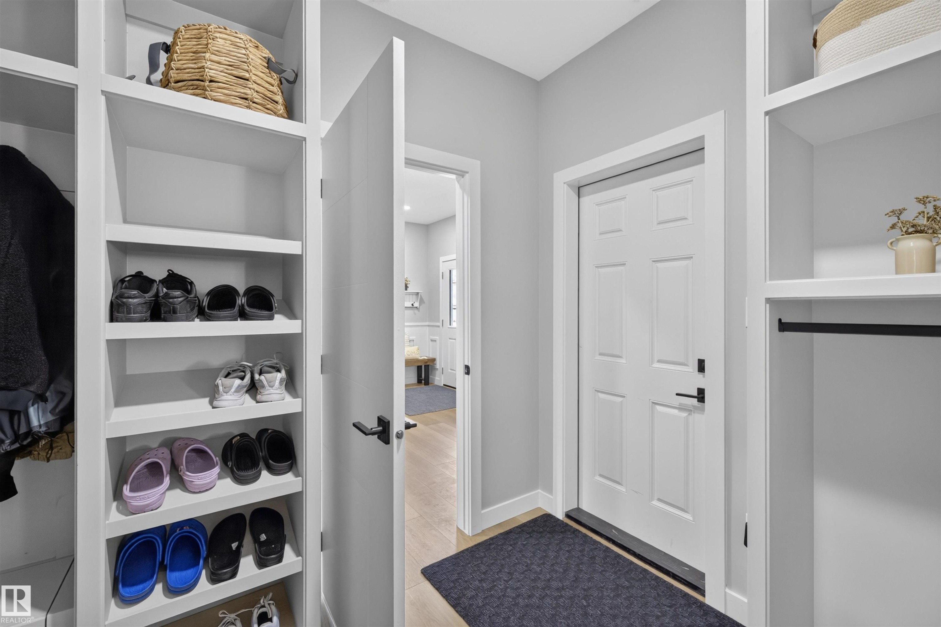 Entryway mudroom featuring integrated shelving units, a coat hanging rod, panel-style door, and light wood-finish flooring - 1573 Esaiw Place Nw, Edmonton, AB