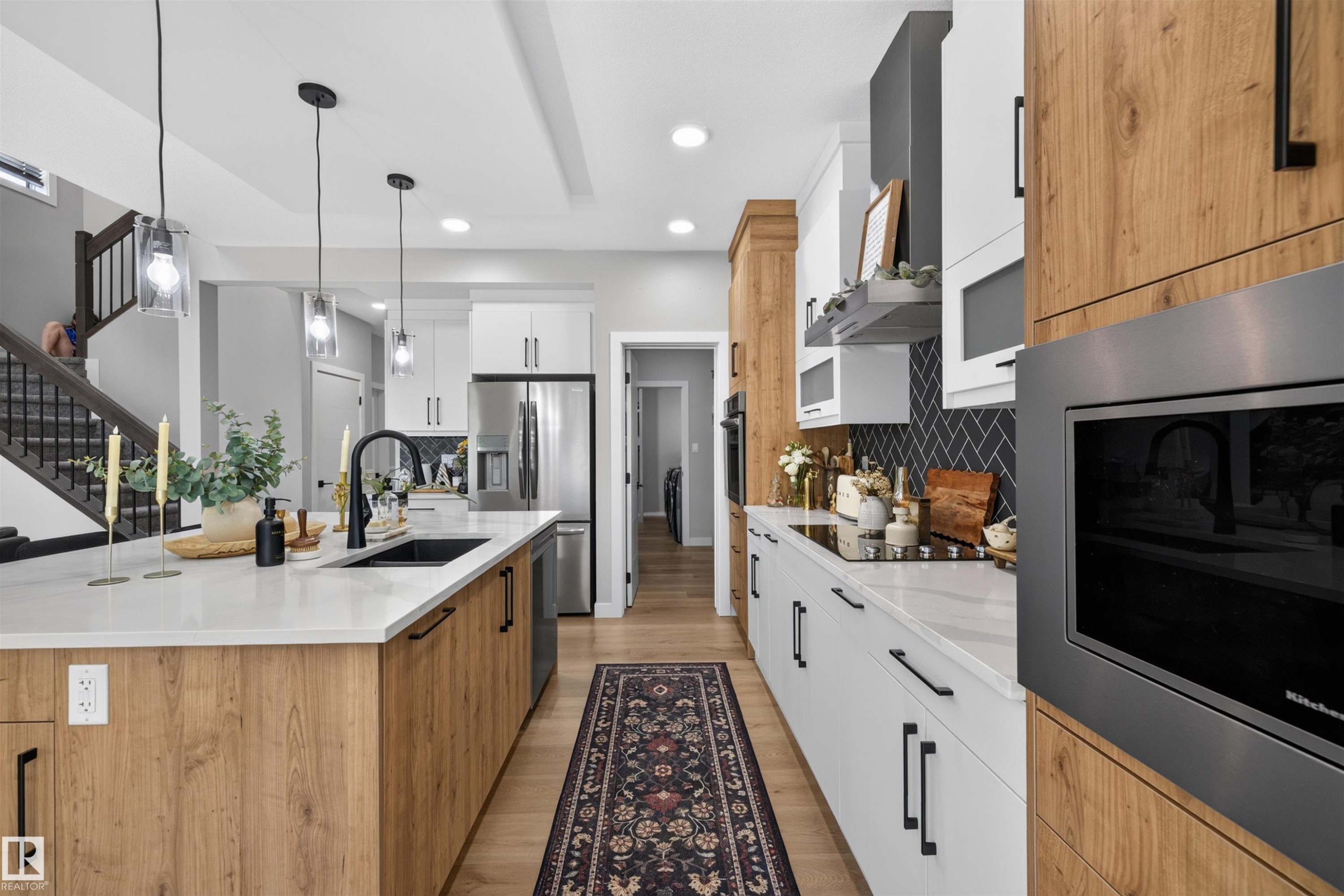 Modern kitchen featuring an expansive island with a built-in sink and pendant lighting - 1573 Esaiw Place Nw, Edmonton, AB