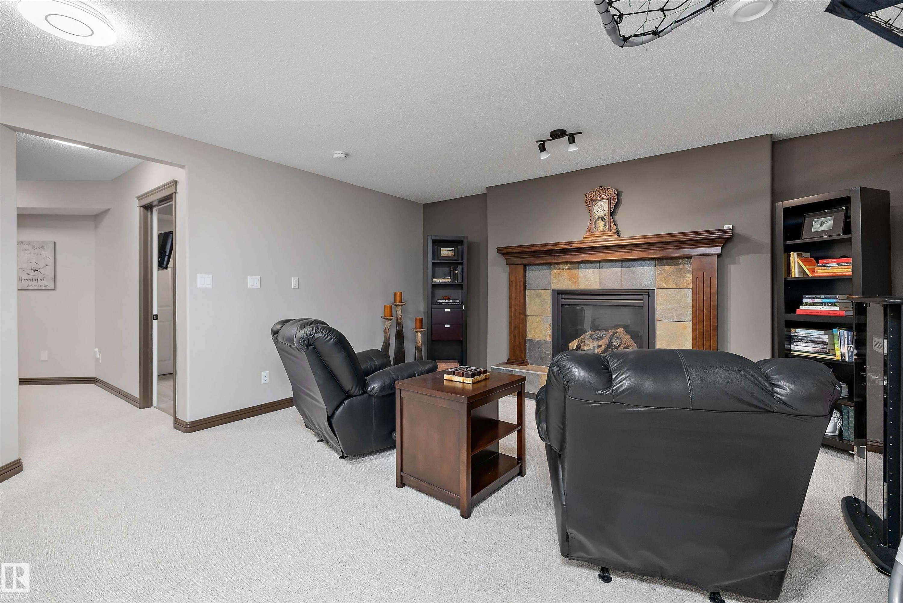 Carpeted room featuring a stone fireplace with a wood mantel - 533 Stewart Crescent, Edmonton, AB