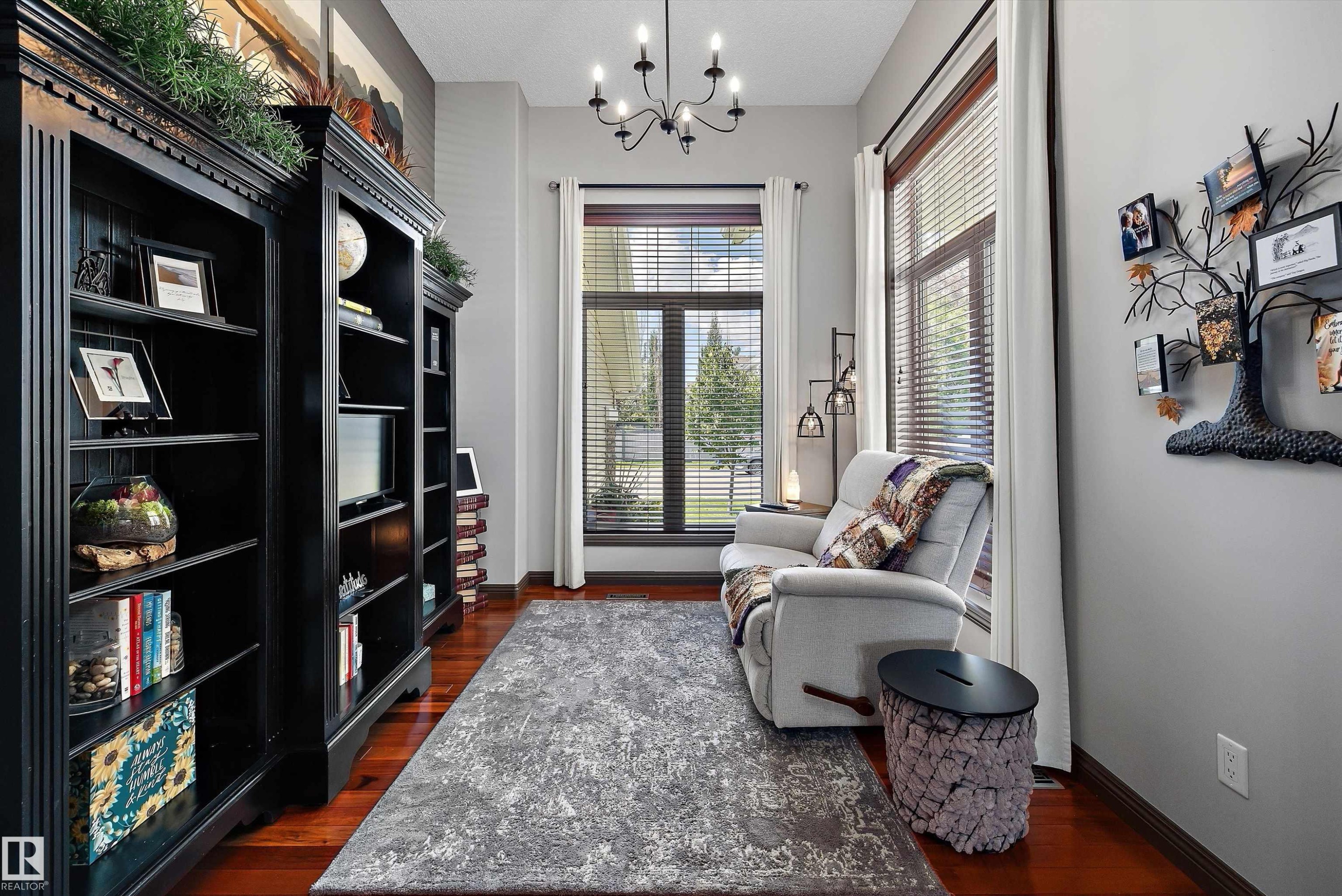 Room featuring rich wood-finish flooring, built-in shelving, large windows with blinds, and a multi-arm chandelier - 533 Stewart Crescent, Edmonton, AB